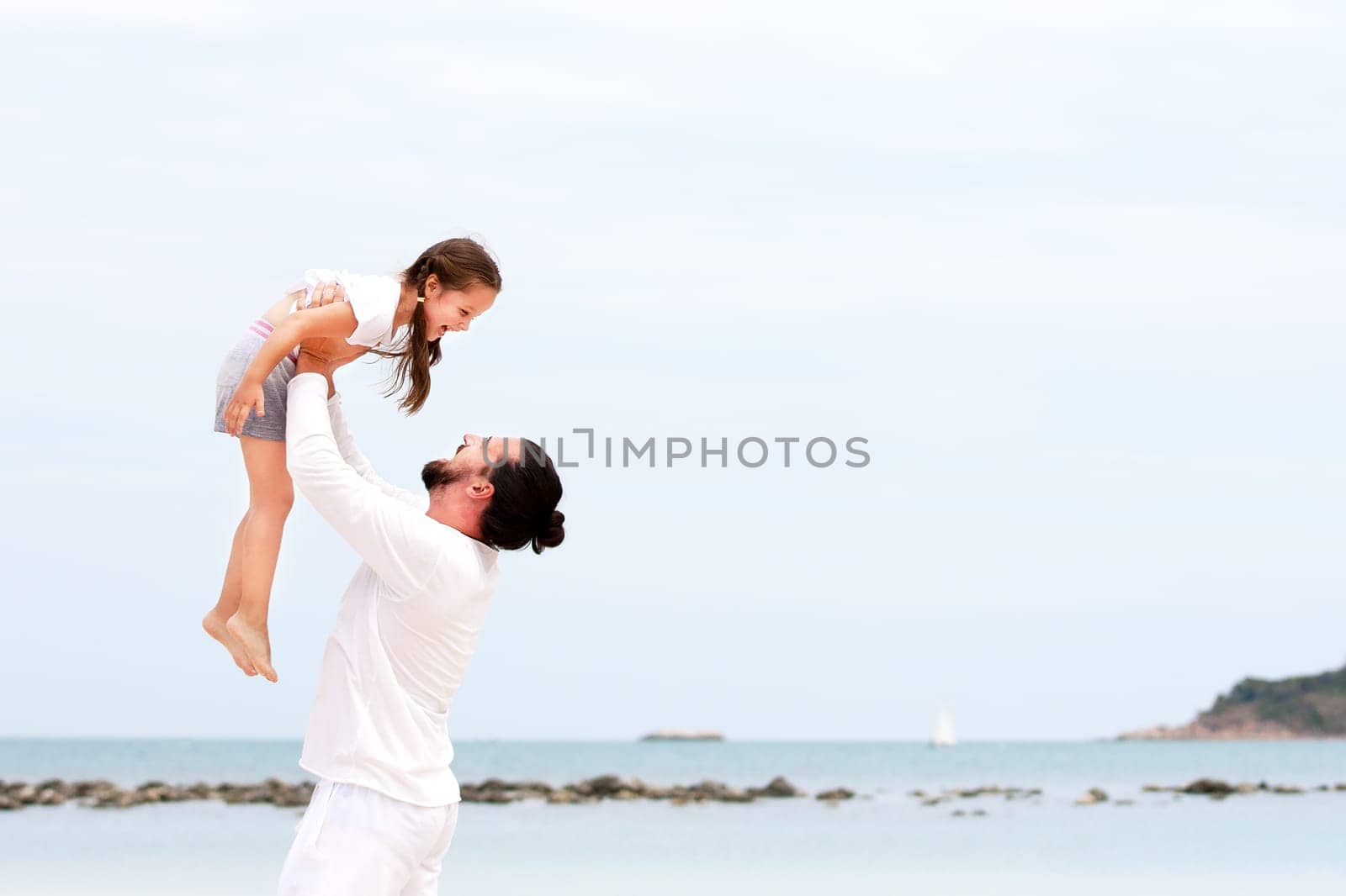 Father and daughter holding hands and walking on deserted tropical beach together happy and loving vacation
