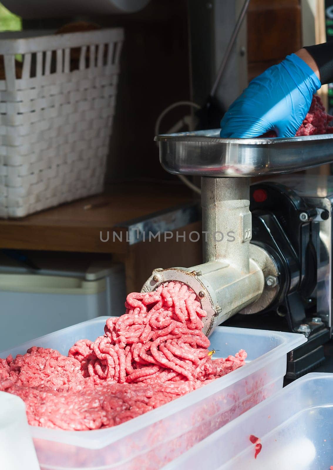 Tray of fresh minced meat. Butcher hand meat grinder and machine that puts the meat back into the machine.