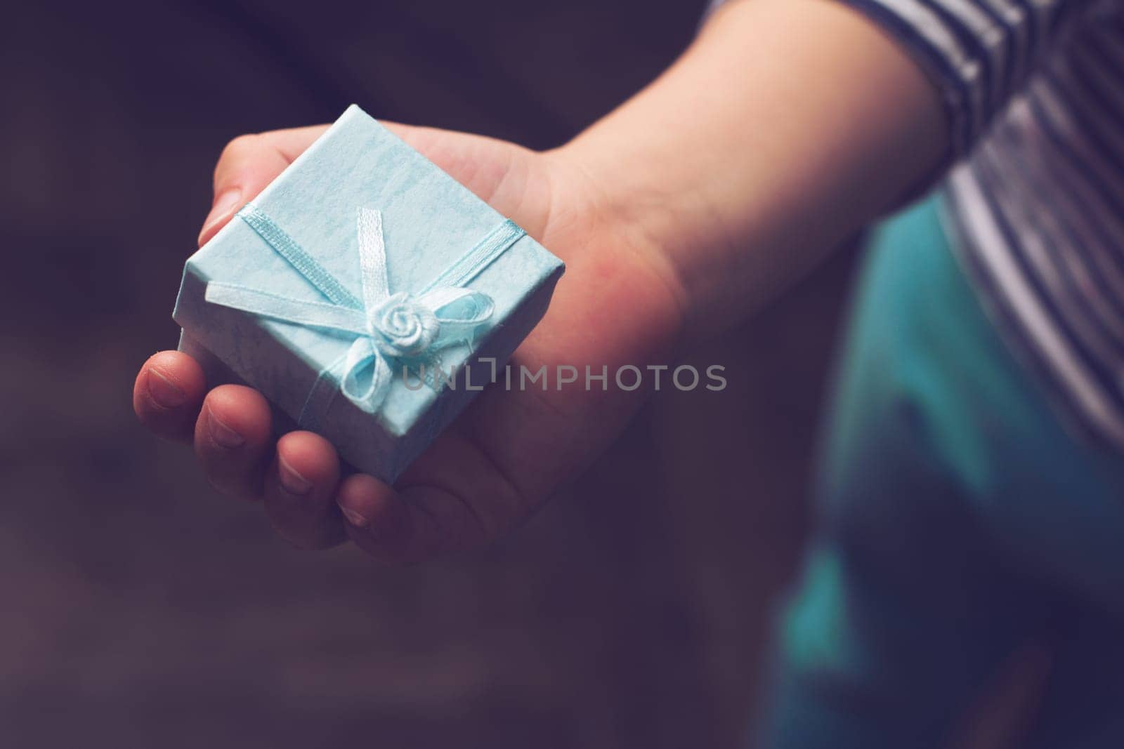 top view close up of child holding a blue gift box with ribbon in his hand