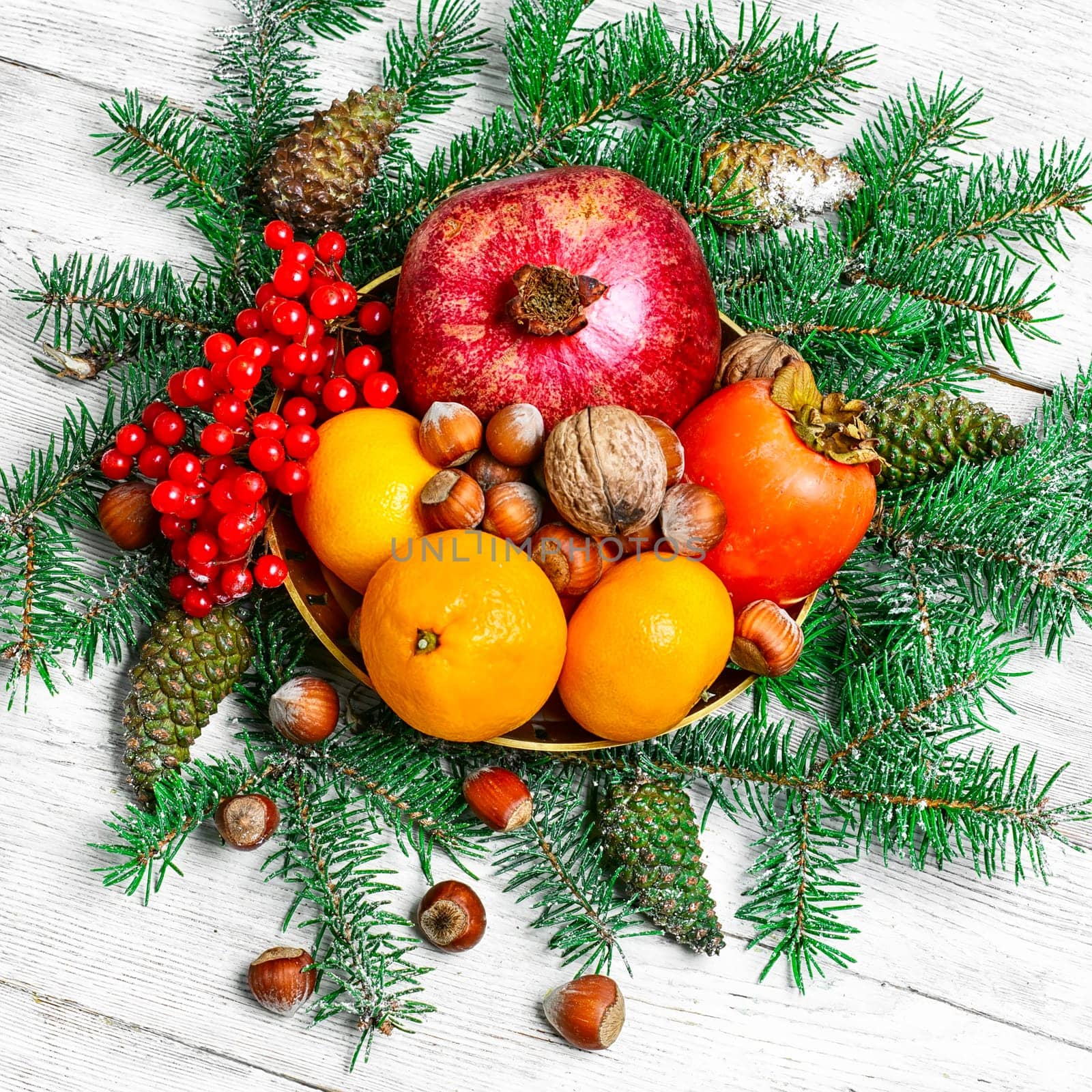 tangerines,pomegranates,persimmons and nuts,decorated with fir branches