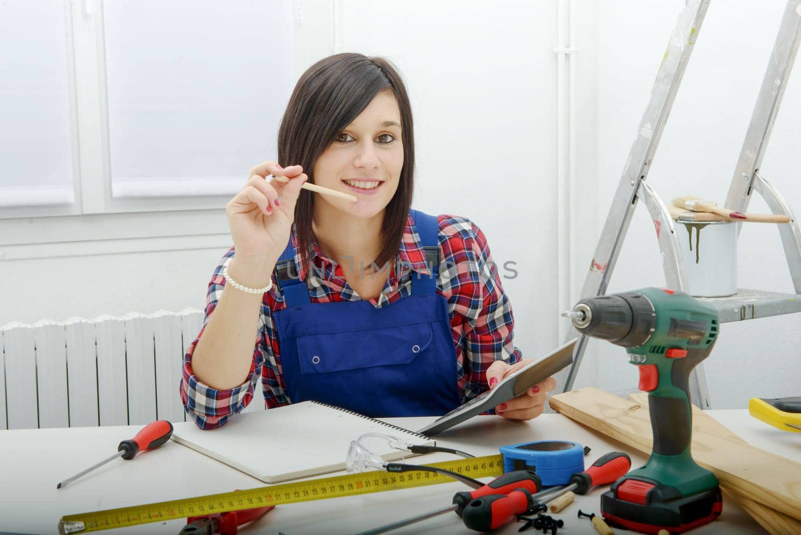 young woman carpenter sitting at desk in her workshop