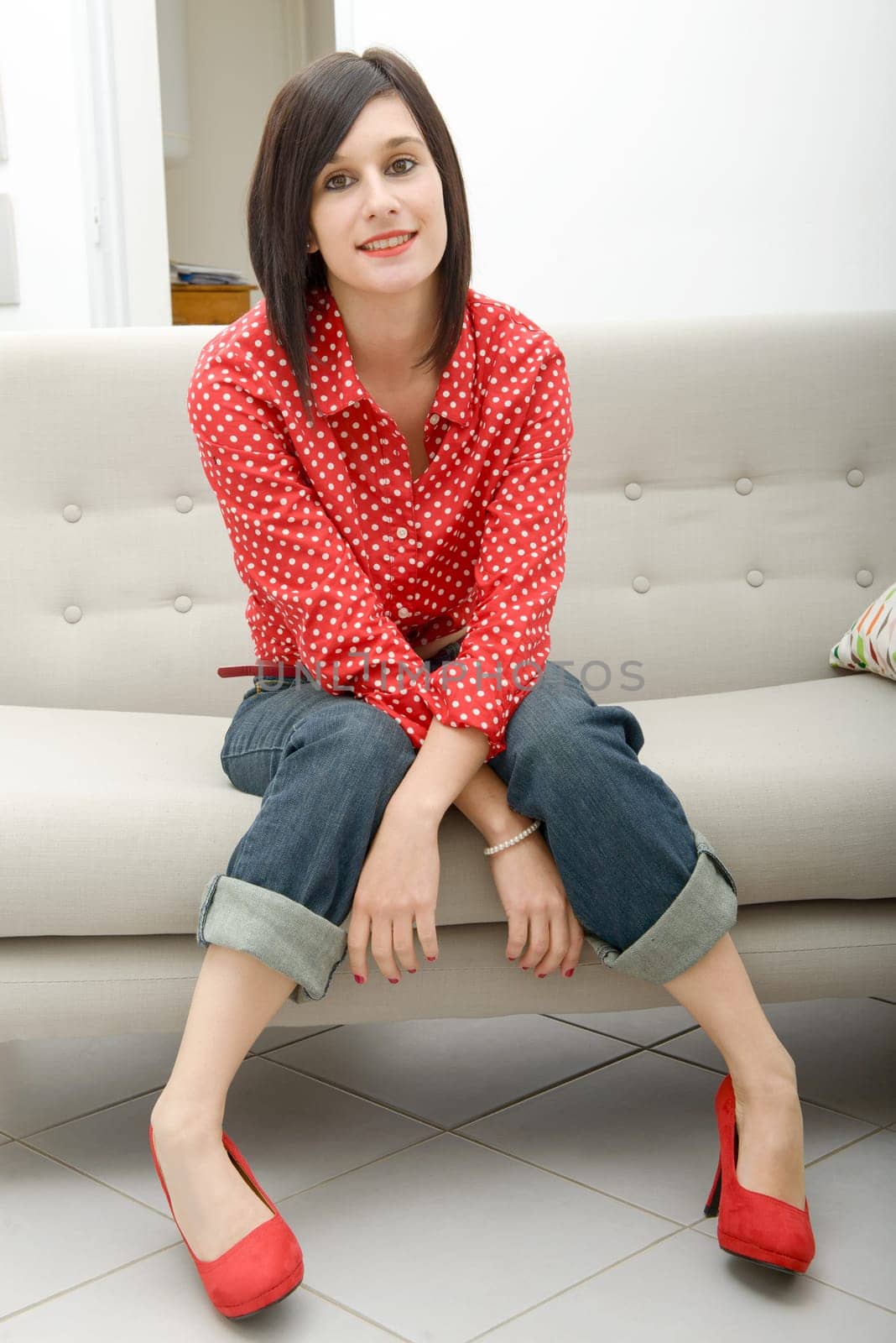 young brunette woman with jeans pants sitting in the sofa