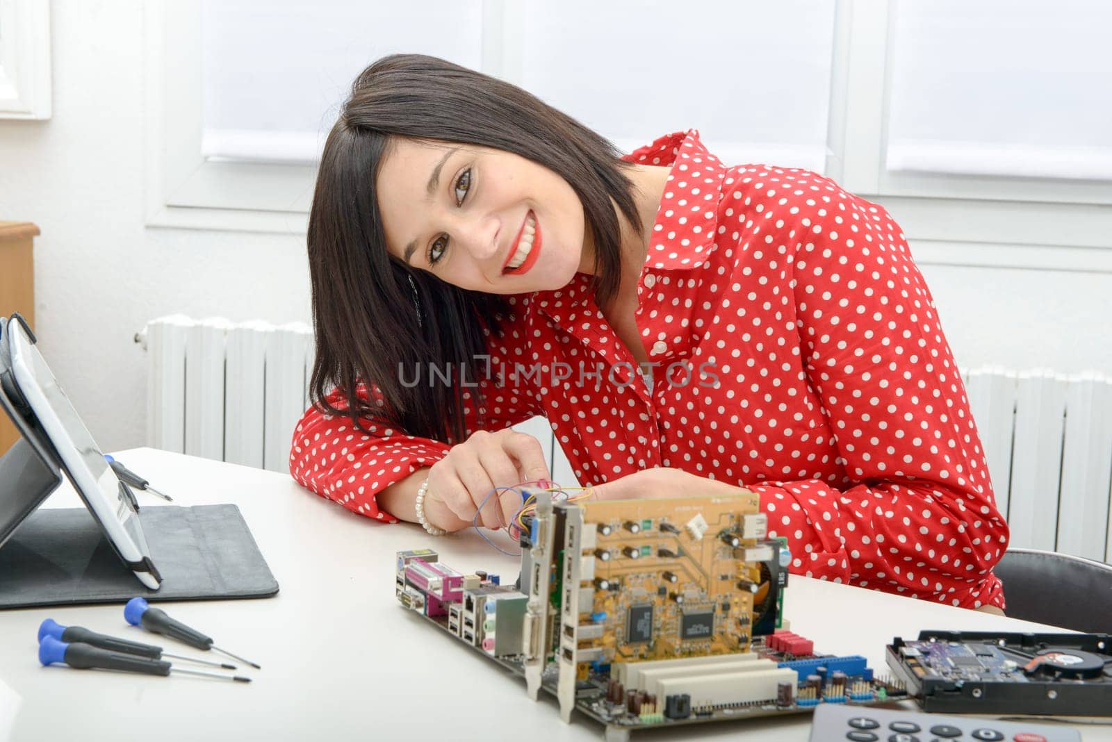 Young smiling brunette woman  technician repairs a computer