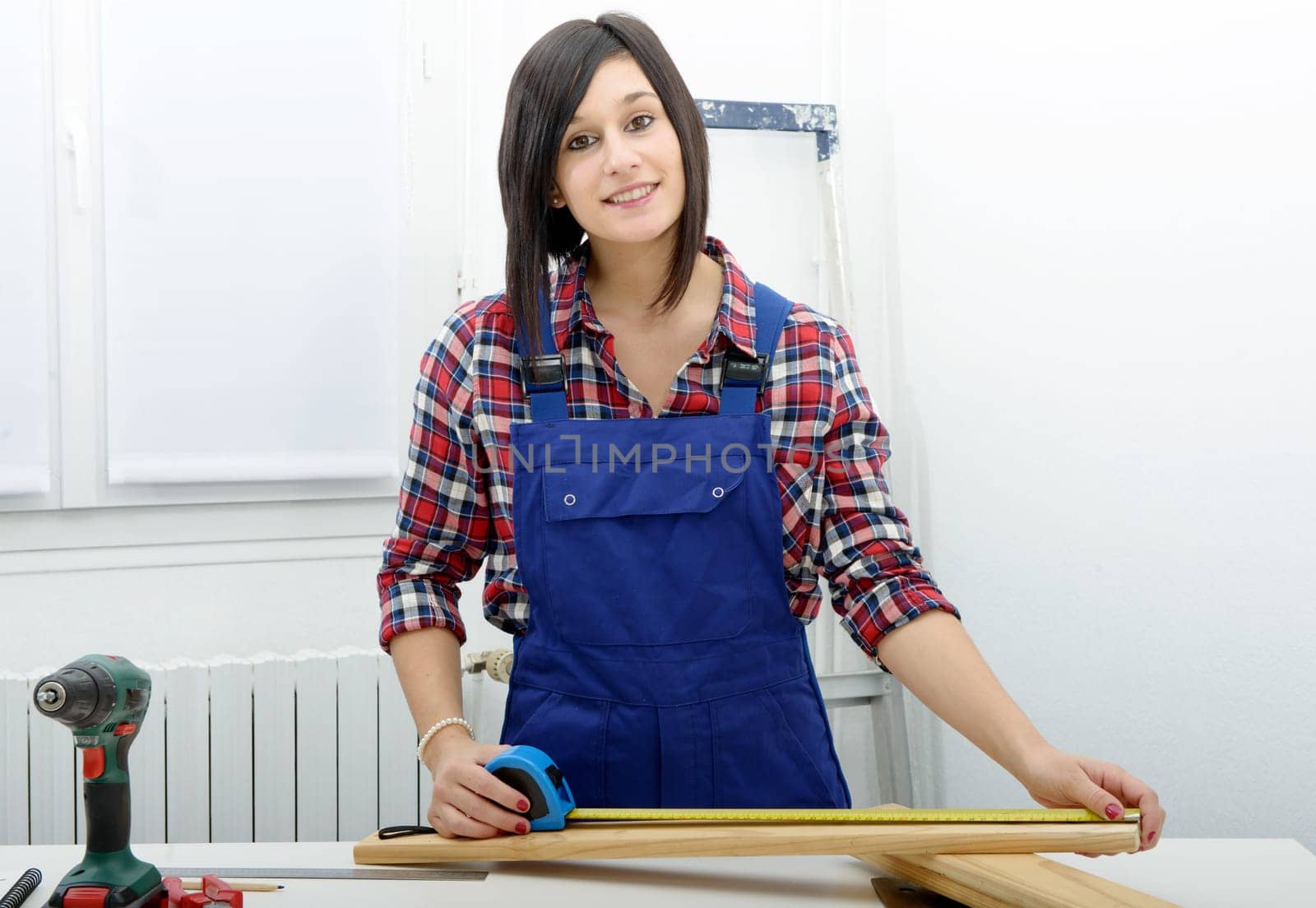 pretty young  woman builder measuring a plank of wood