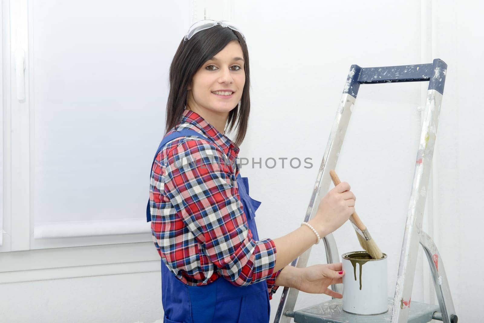pretty young woman paints the wall green color