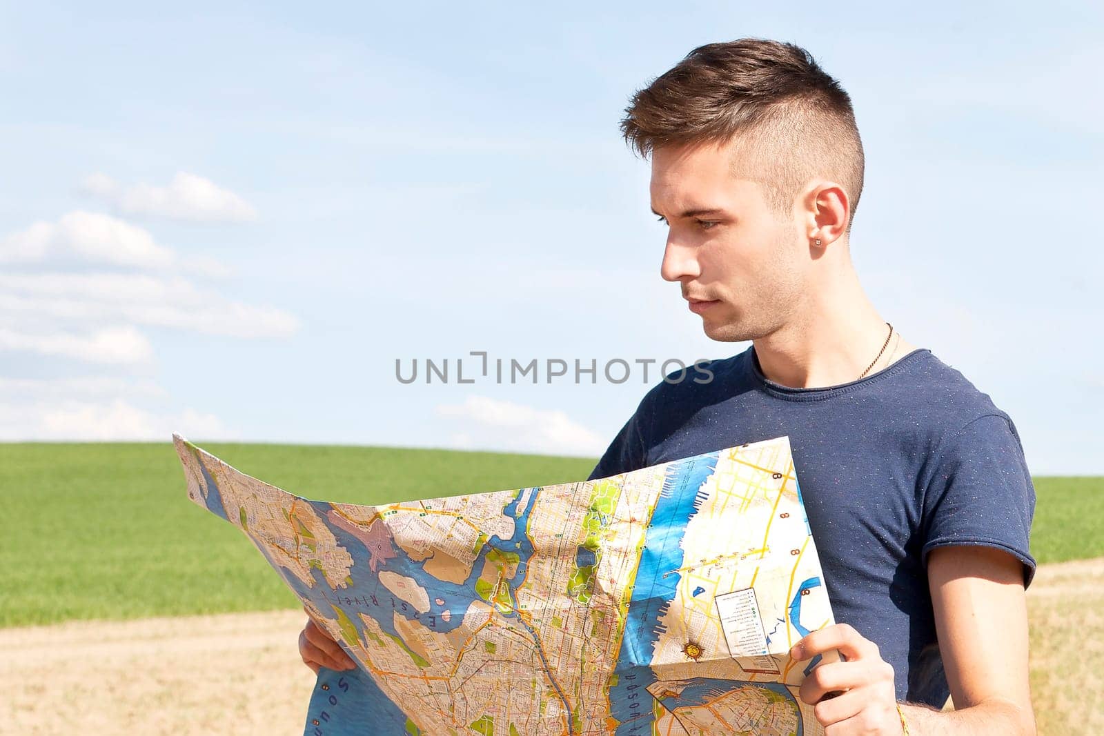 Photo of a traveler parked his car by the side of a road, lost and reading the NYC map. Focus on the map and male.