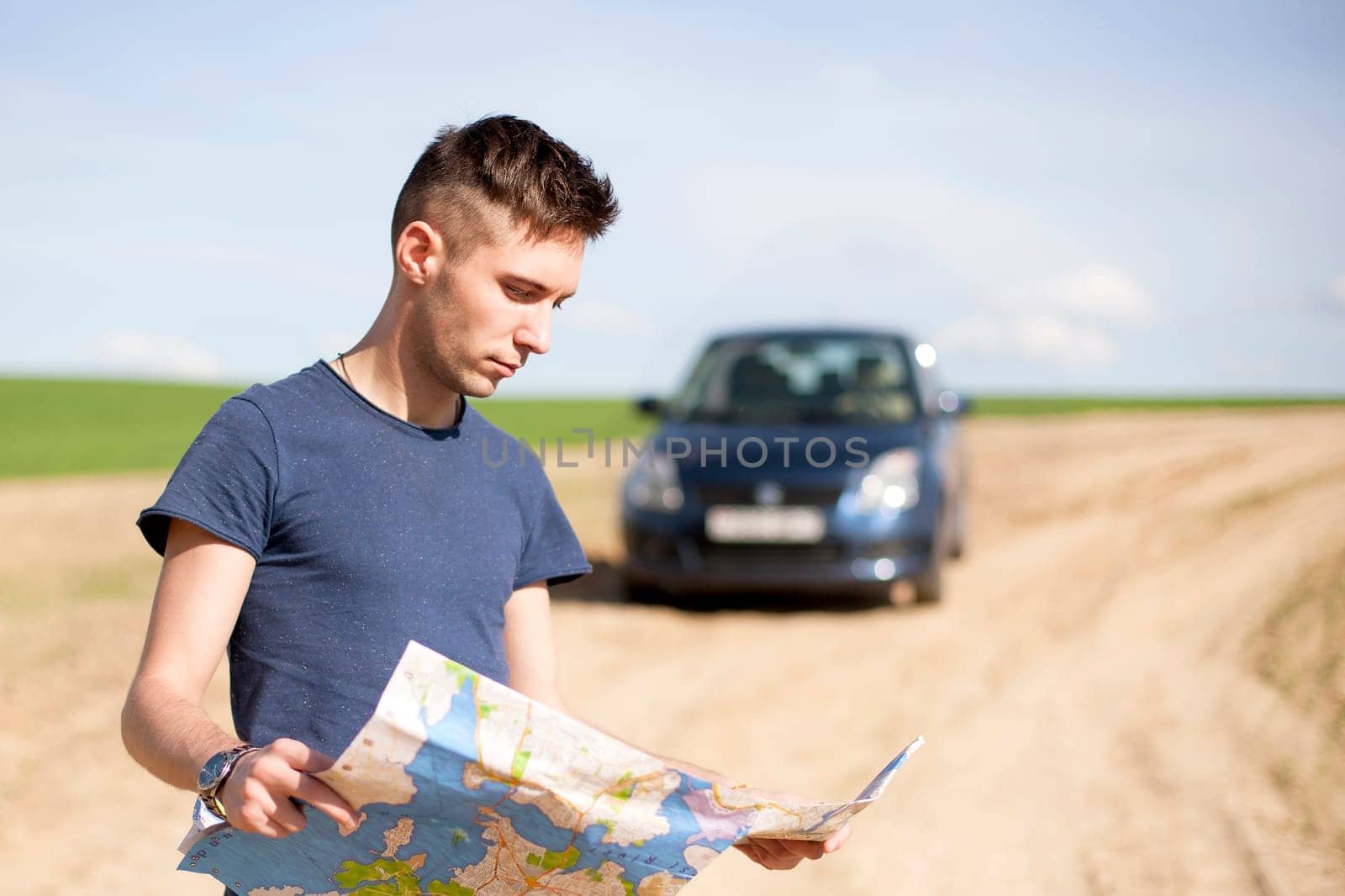 Photo of a traveler parked his car by the side of a road, lost and reading the NYC map. Focus on the map and male.