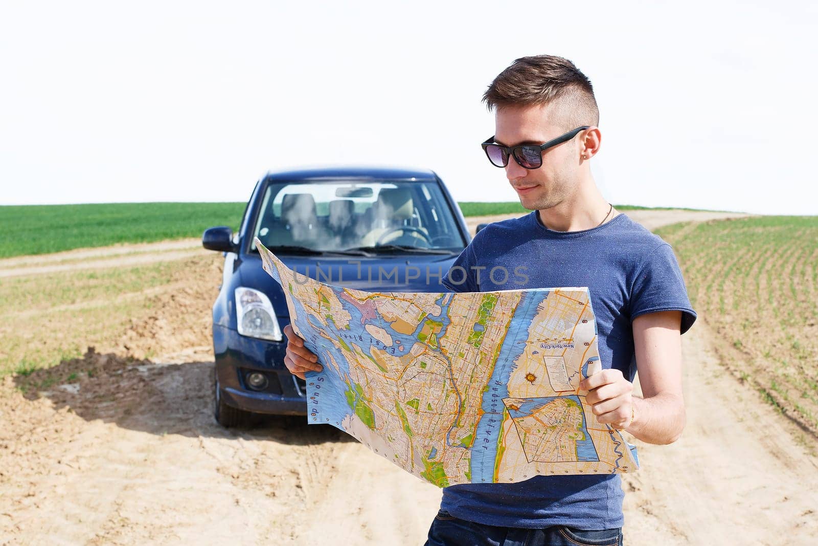 Photo of a traveler parked his car by the side of a road, lost and reading the NYC map. Focus on the map and male.
