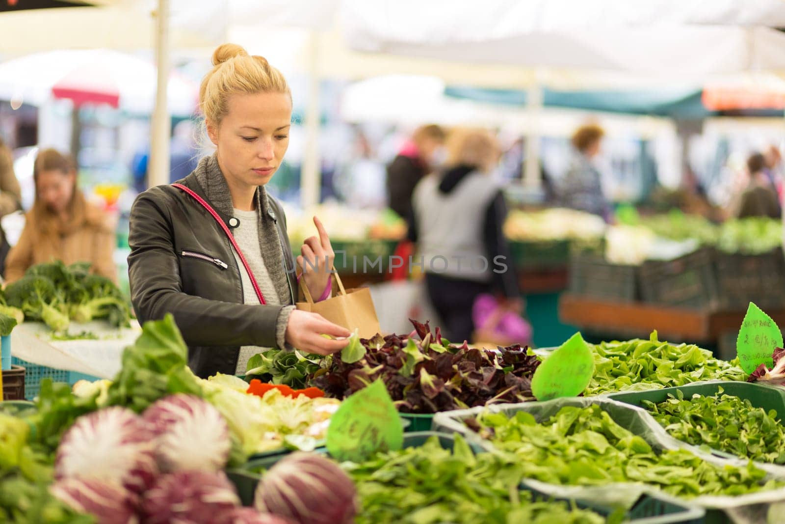 Woman buying fruits and vegetables at local food market. Market stall with variety of organic vegetable.