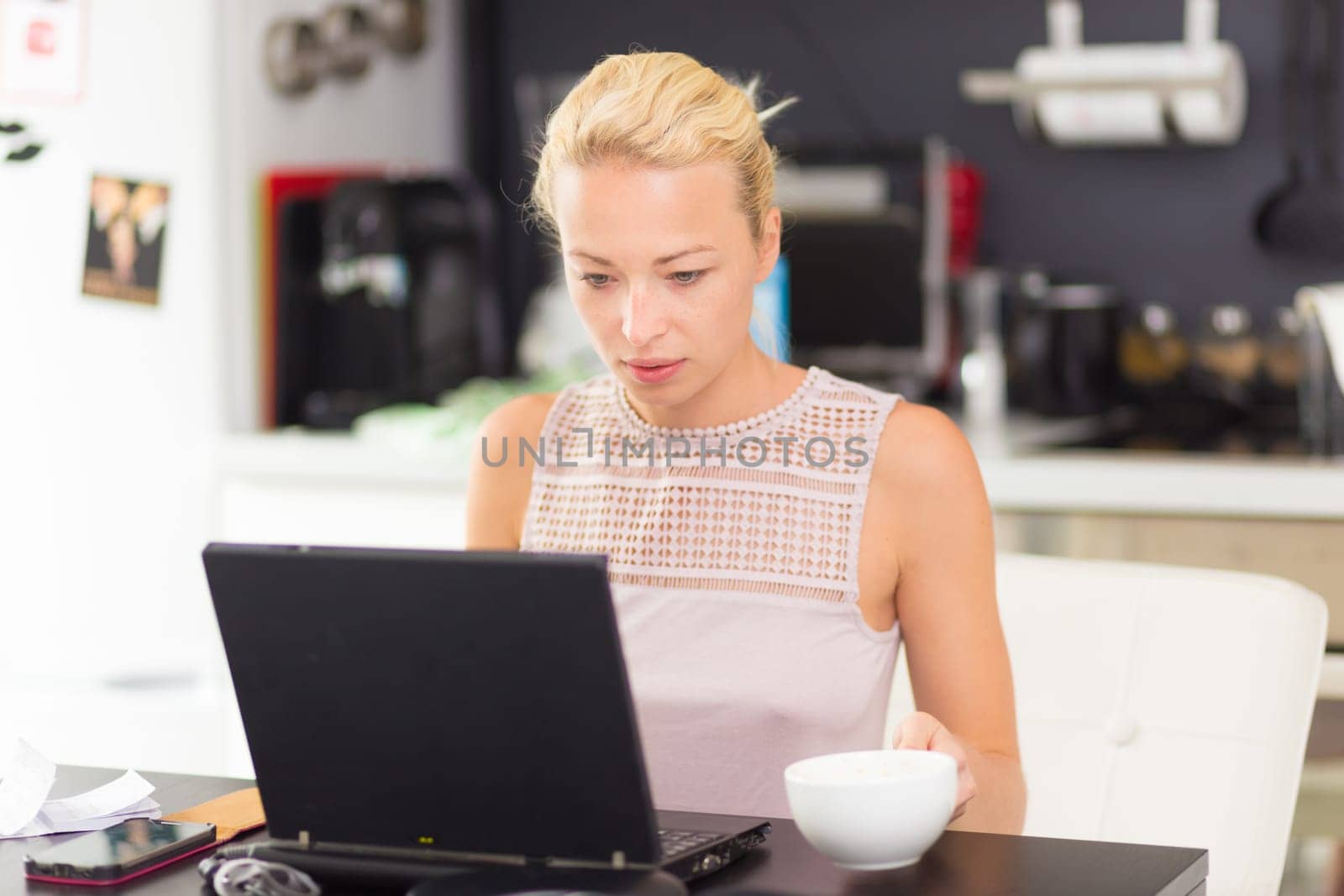 Business woman working remotly from her dining table. Home kitchen in the background.