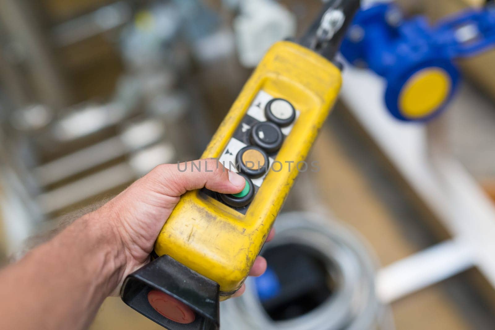 Industrial worker pushing on button of machinery control panel in manufactury.