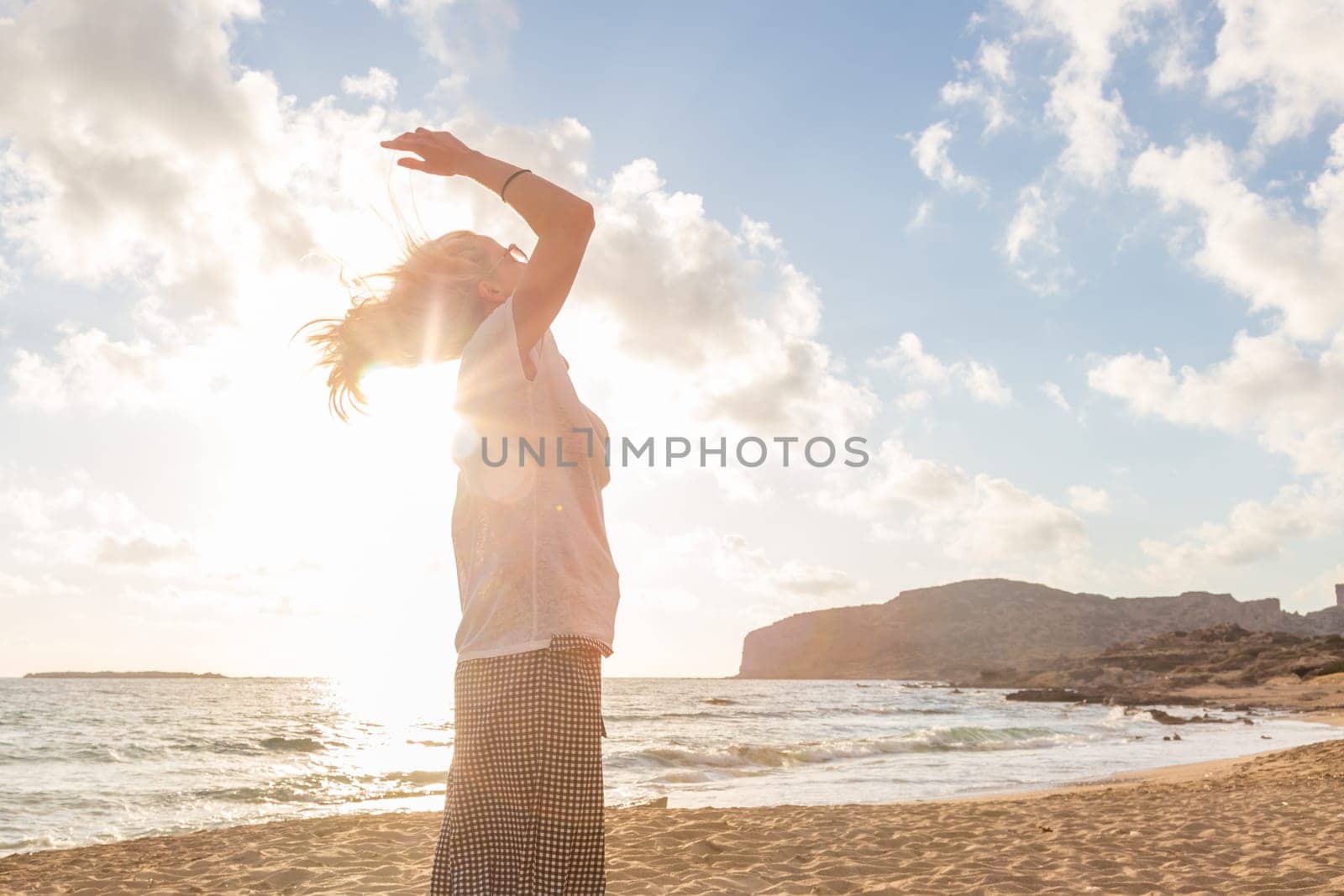 Relaxed woman enjoying sun, freedom and life an a beautiful sandy beach. Young lady feeling free, relaxed and happy. Vacations, freedom, happiness, enjoyment and well being.