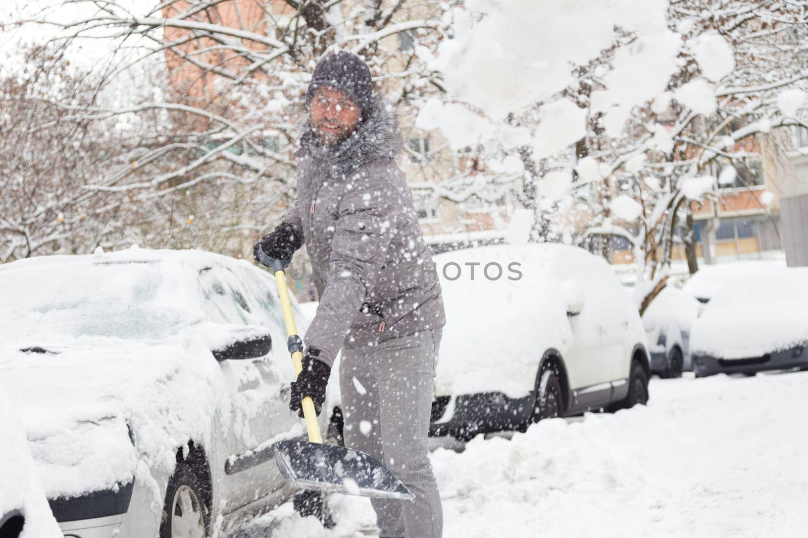 Man shoveling her parking lot after a winter snowstorm.