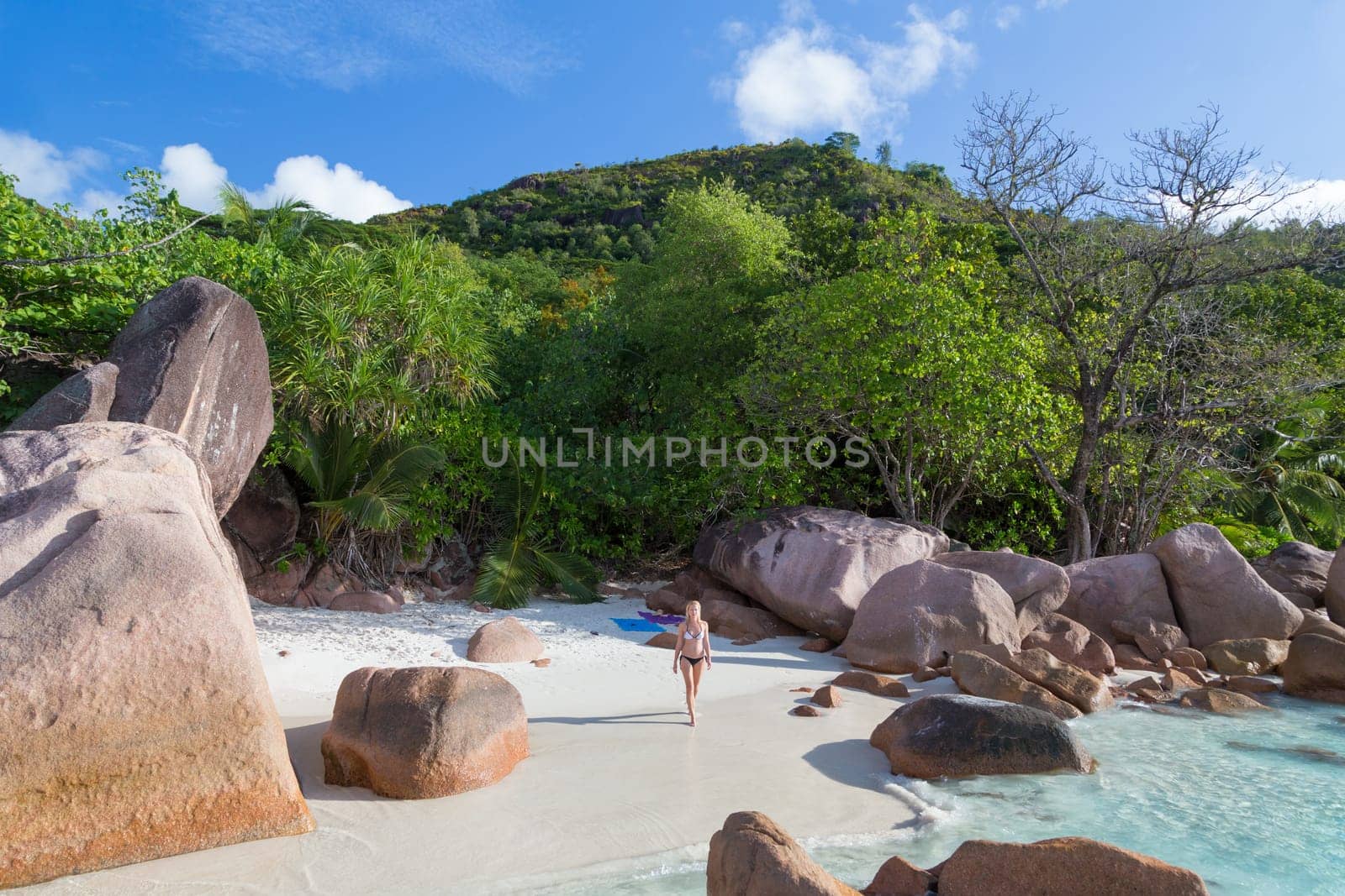 Happy woman wearing stylish bikini enjoying at amazing Anse Lazio beach on Praslin Island, Seychelles. Summer vacations on picture perfect tropical beach concept.