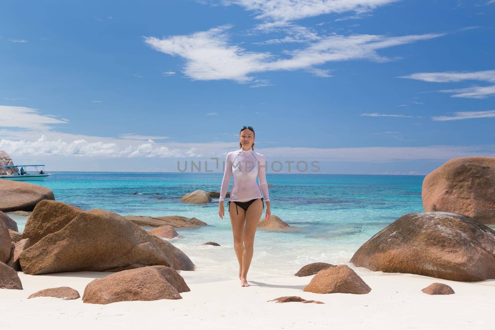 Woman wearing stylish bikini and lycra top enjoying swimming and snorkeling at amazing Anse Lazio beach on Praslin Island, Seychelles. Summer vacations on picture perfect tropical beach concept.