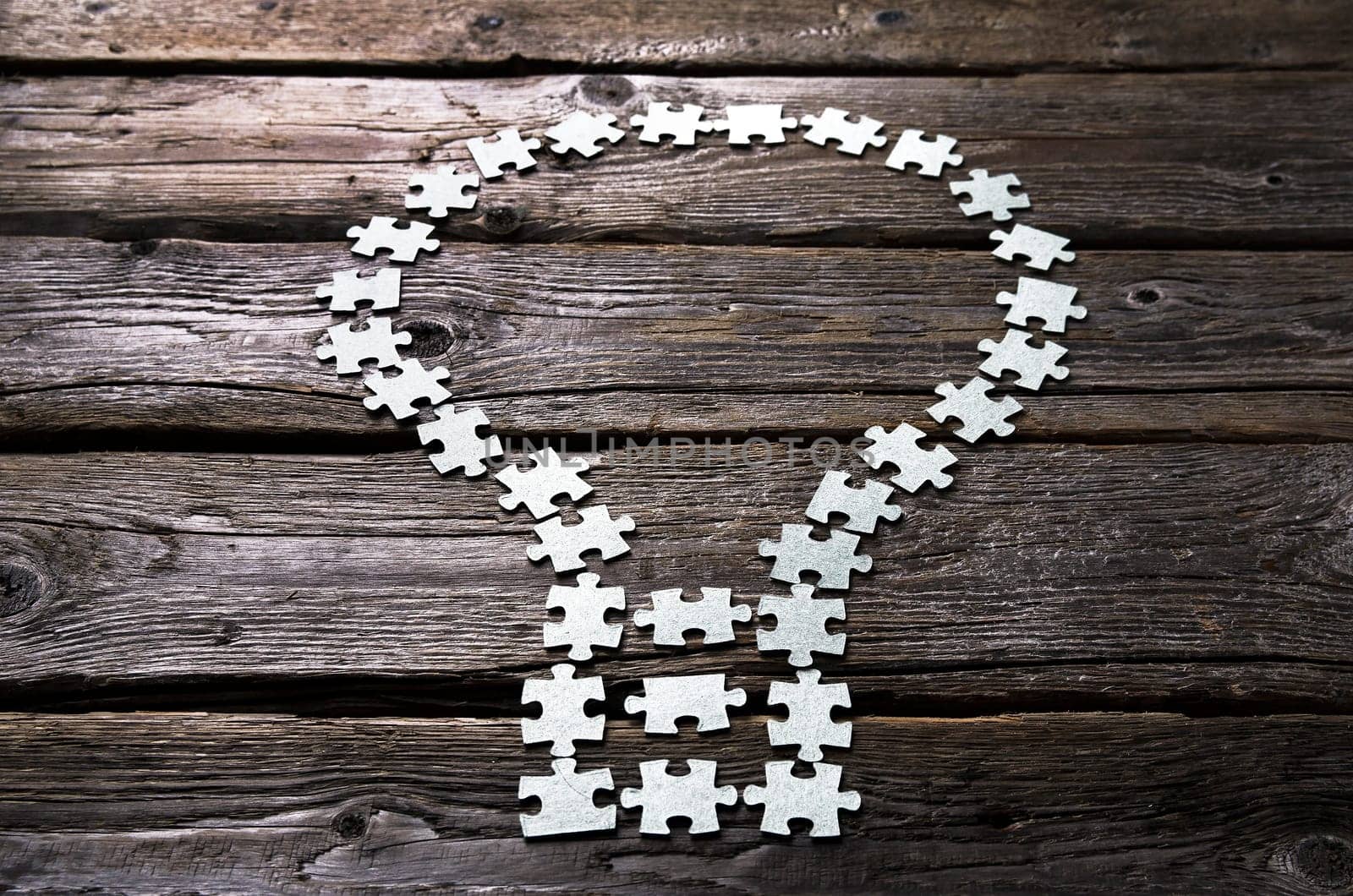 light bulb Lamp made of blank puzzle pieces on a textured wooden table.