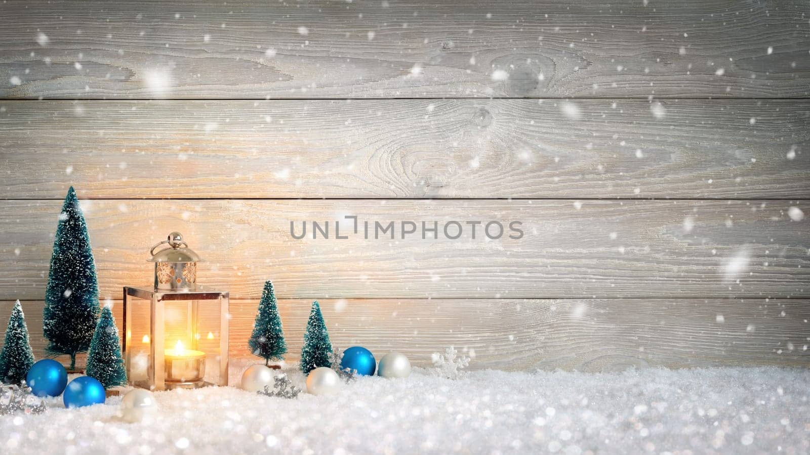 Christmas background with wooden board,falling snow,a burning candle in a lantern and ornaments