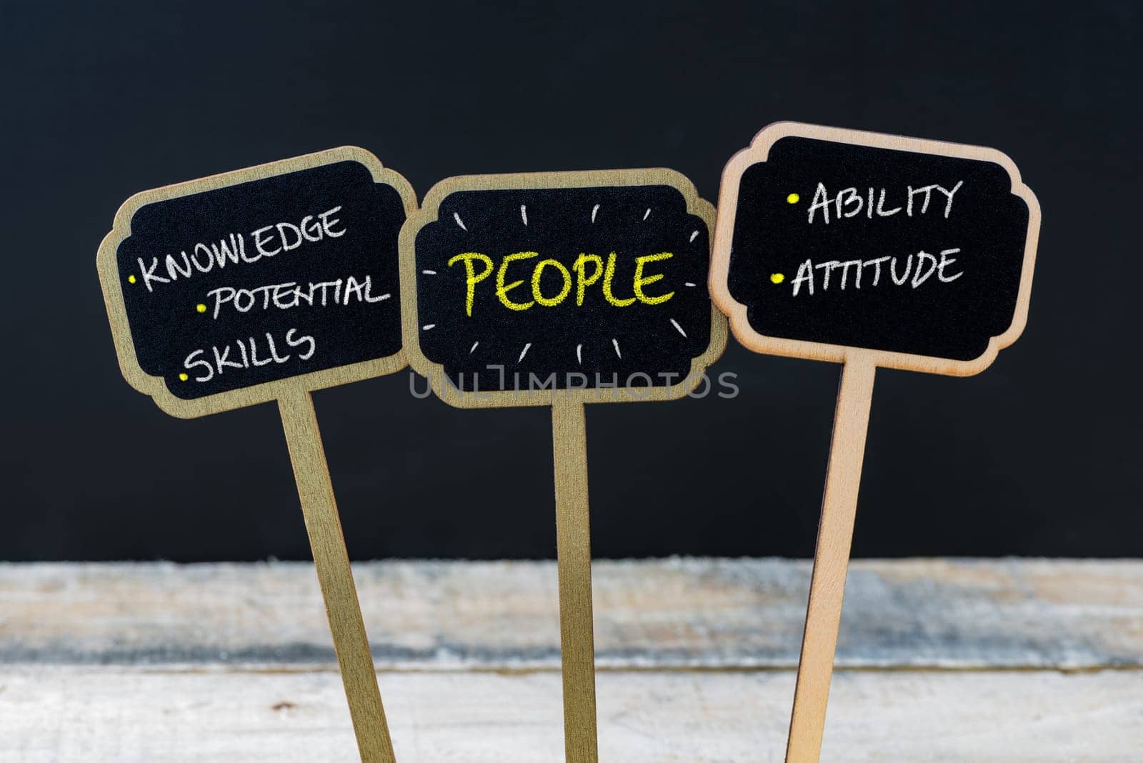 Concept message PEOPLE written with chalk on wooden mini blackboard labels, defocused chalkboard and wood table in background