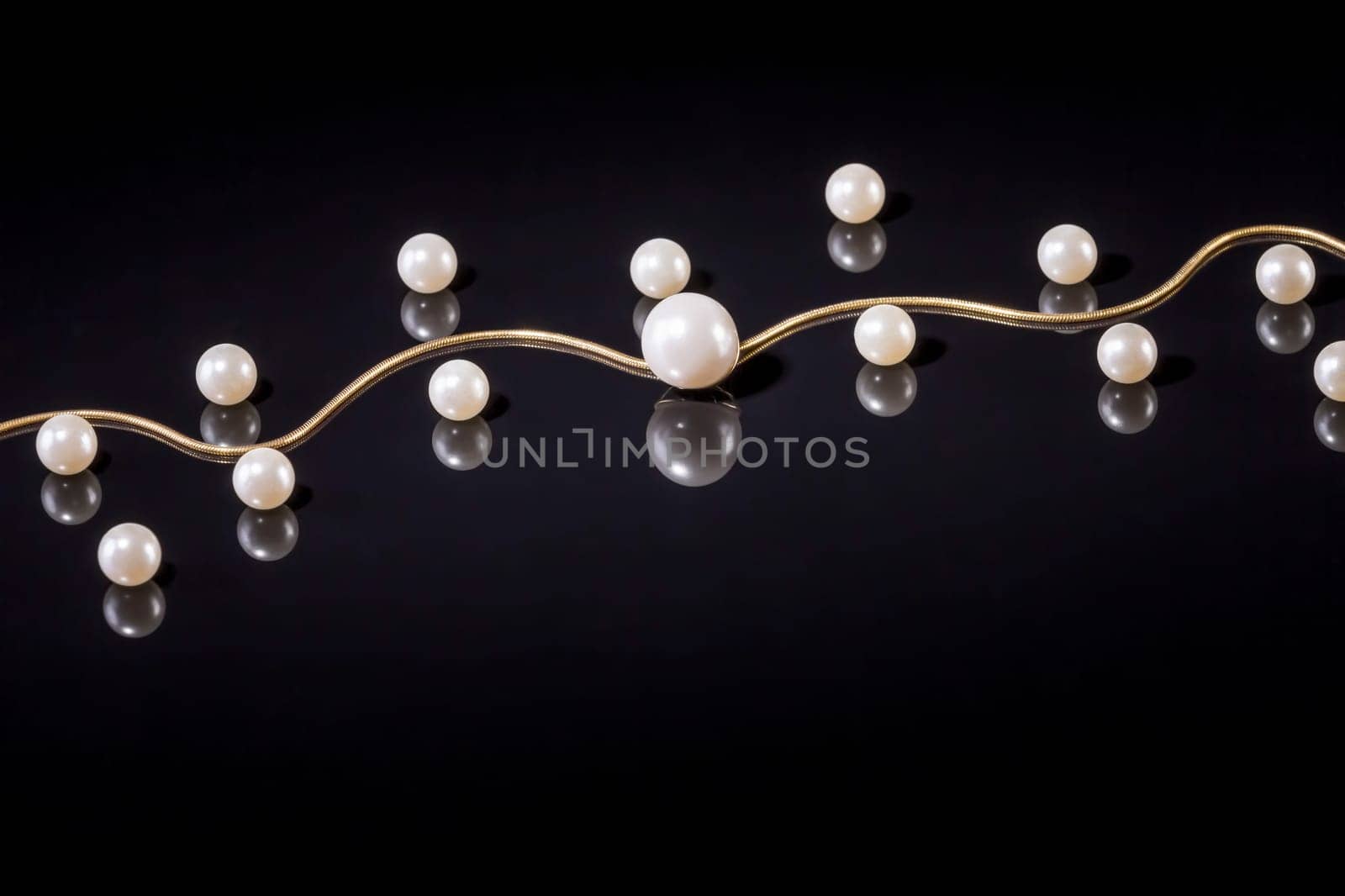 White pearls necklace on black background. Focus on the big pearl!