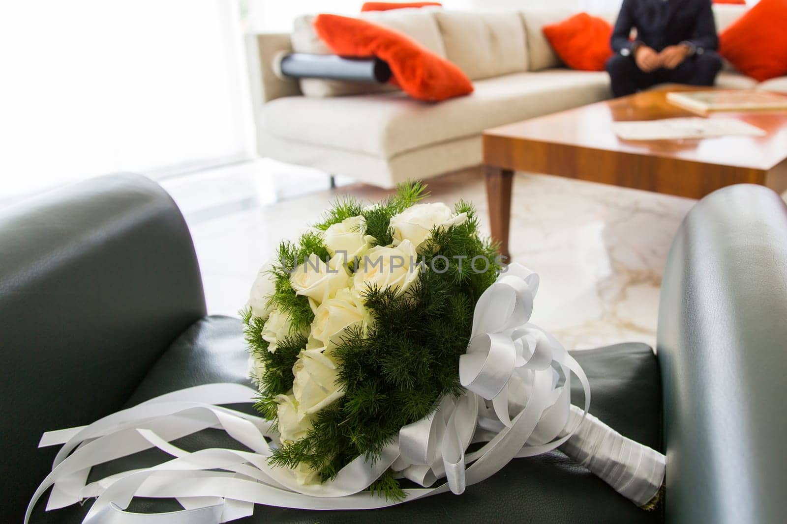 Close up view of a bridal bouquet with him sitting in the background groom