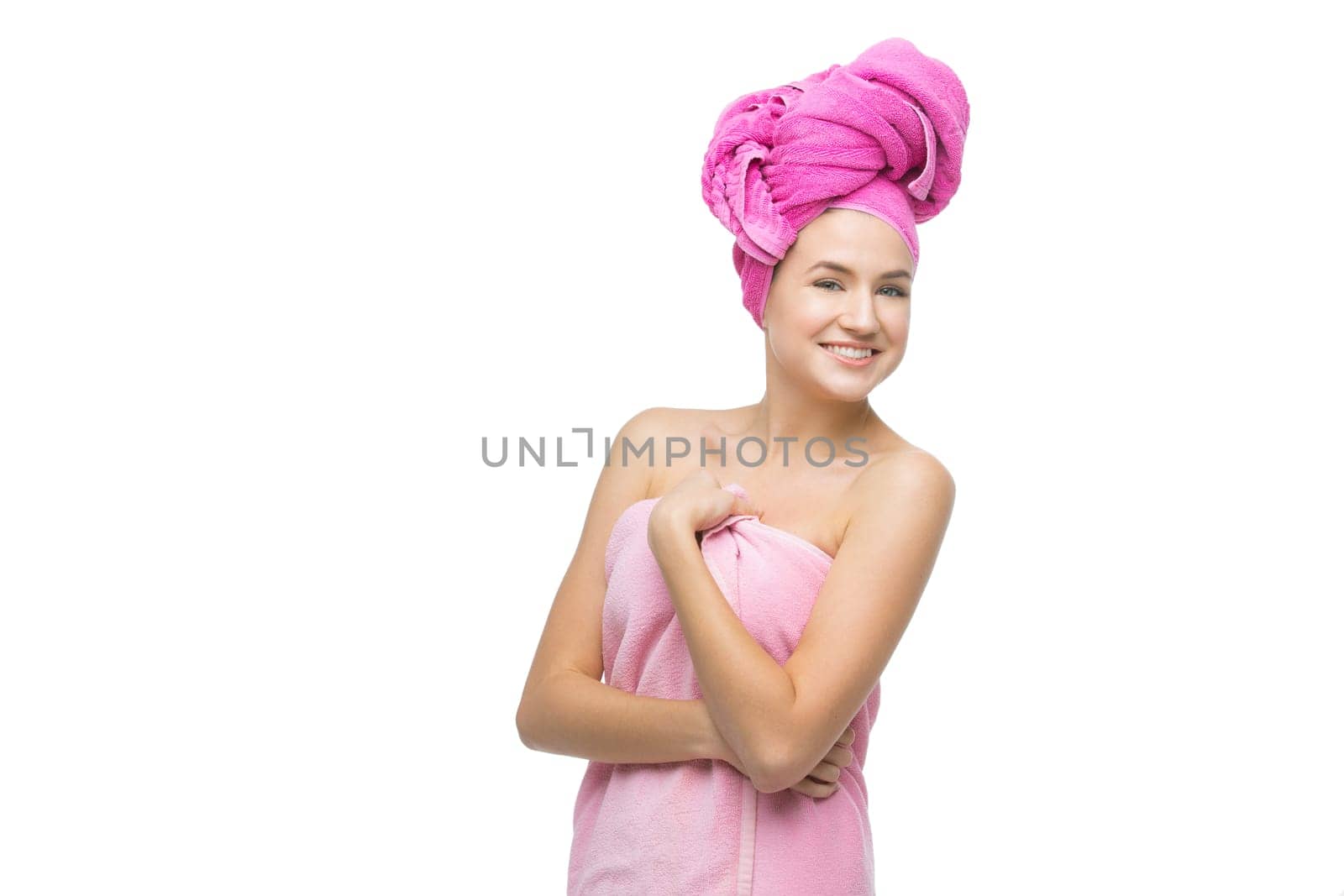 Beautiful young woman with hair and body wrapped in pink towel. Isolated over white background. Copy space.