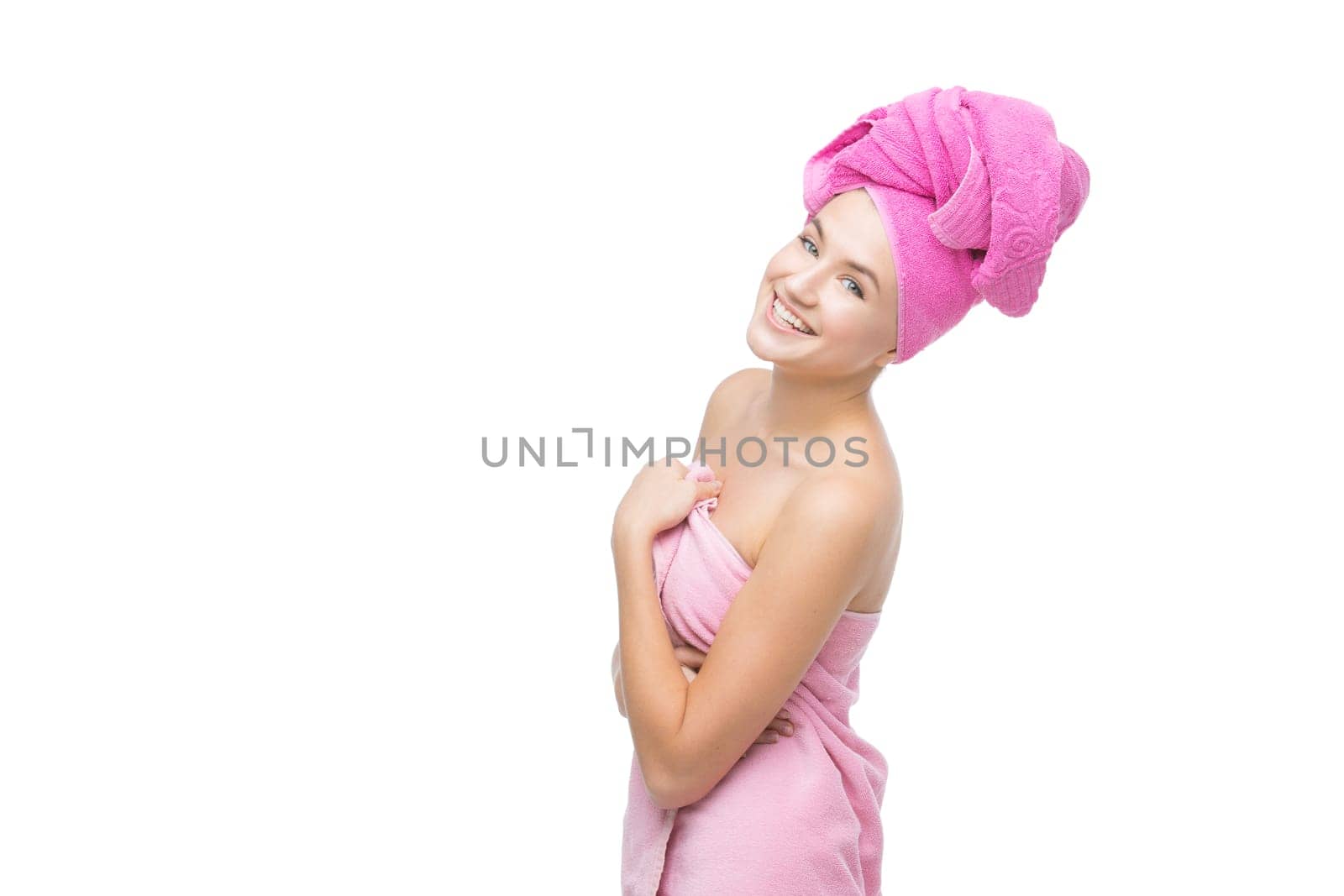 Beautiful young woman with hair and body wrapped in pink towel. Isolated over white background. Copy space.