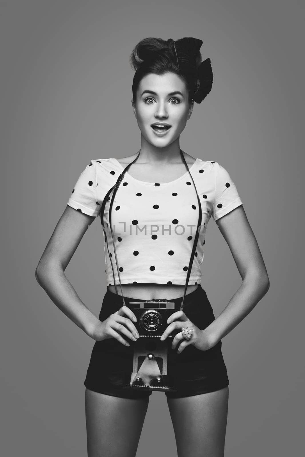 Beautiful young woman with retro photo camera. Surprised expression.