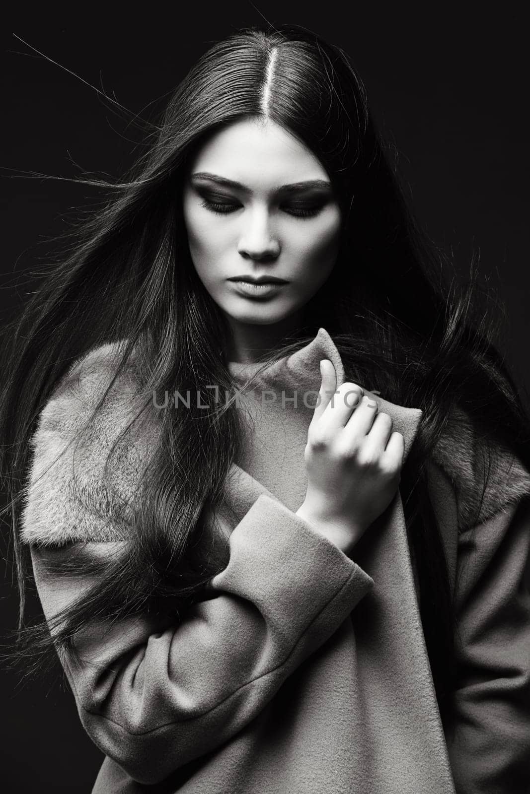 Beautiful young girl with bright makeup wearing coat over dark background