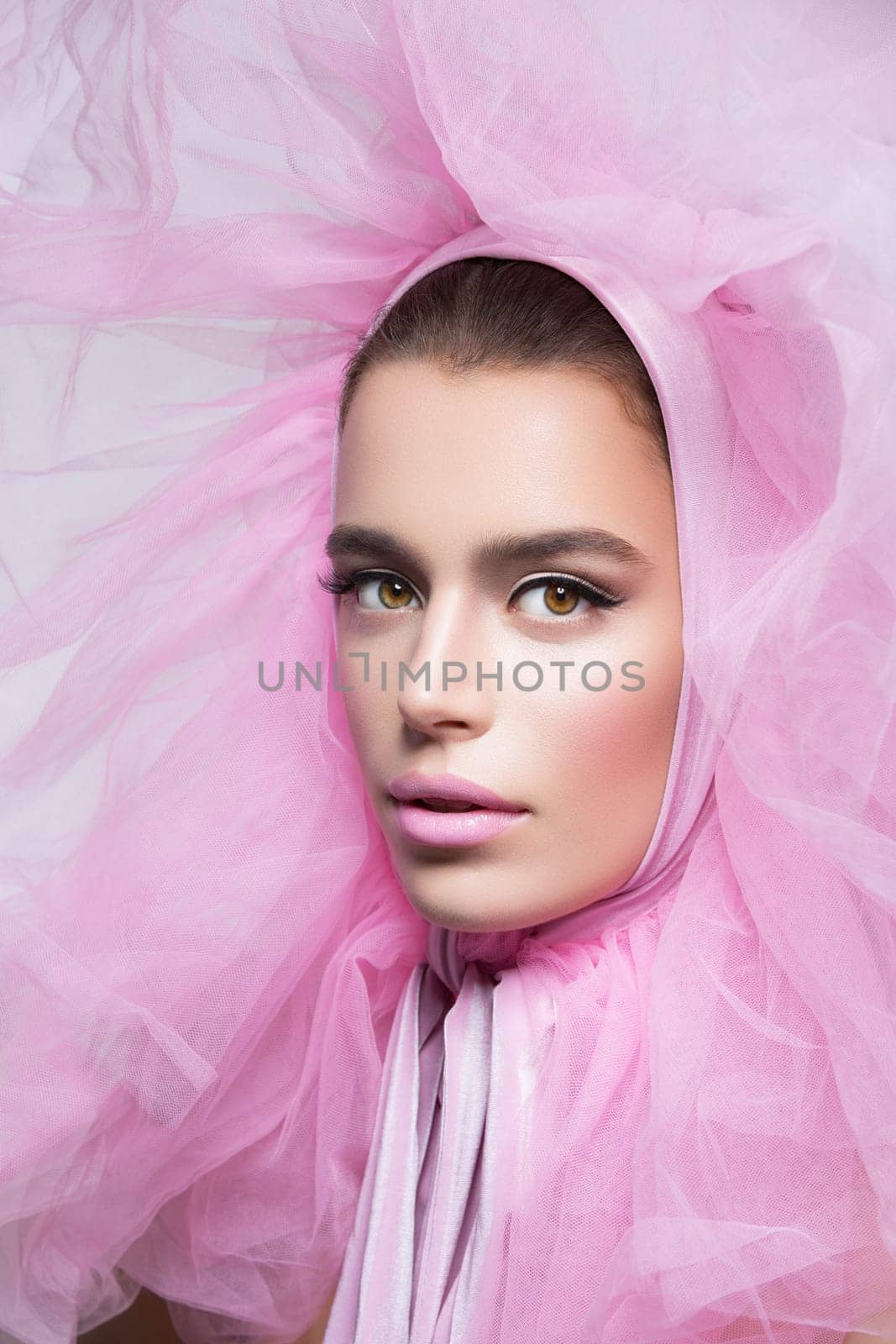 Beautiful young woman in fluffy pink headwear. Close up. Beauty shot. Over grey background.