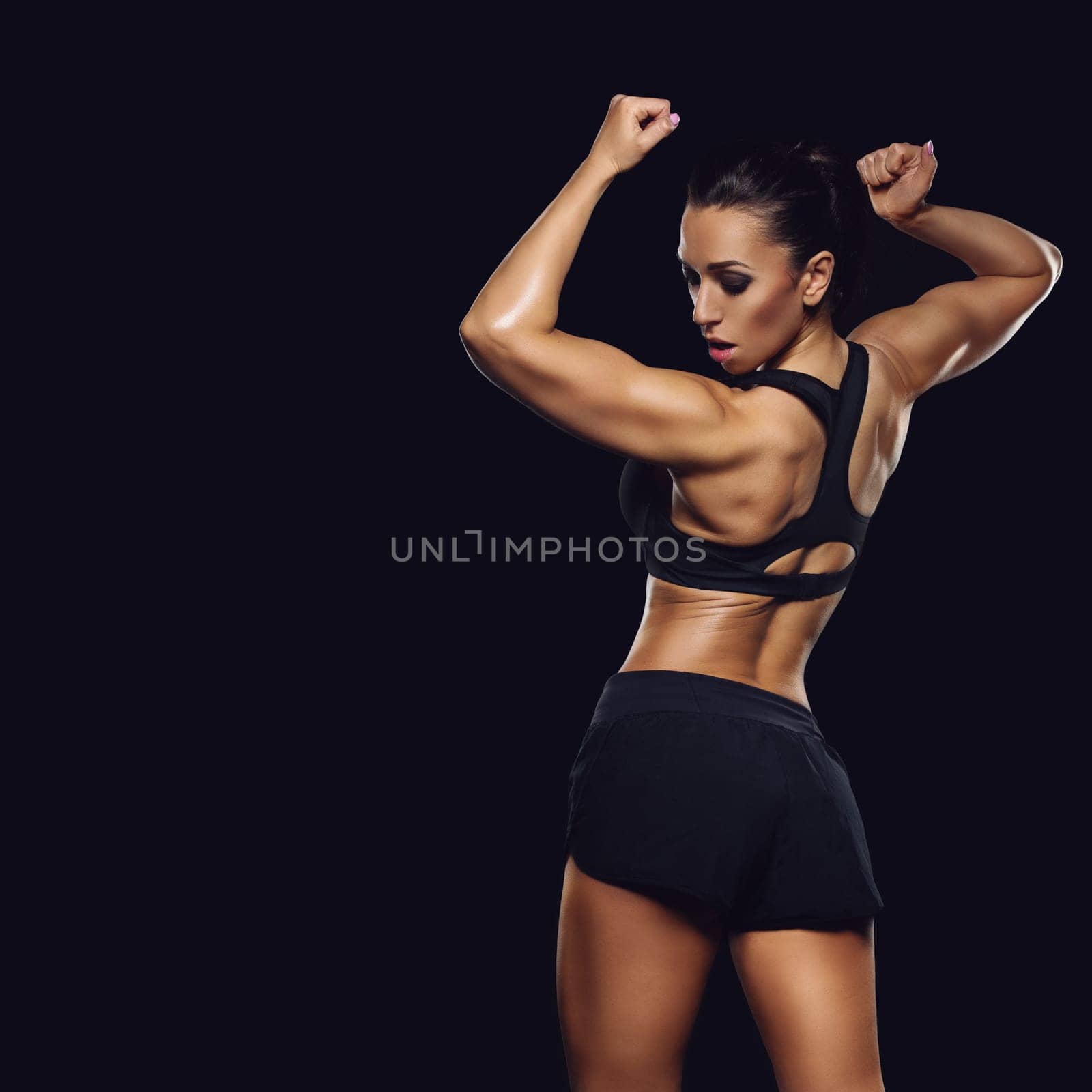 Sporty fit beautiful woman with muscle relief. Over black backgound. Copy space. Square composition.