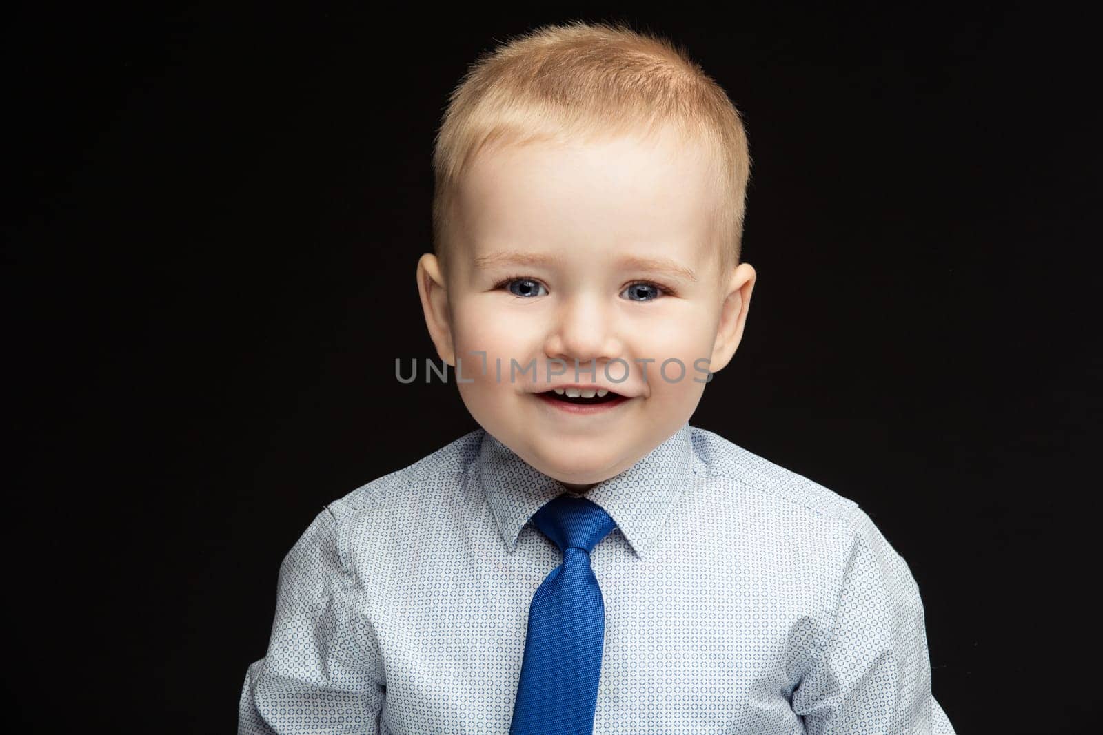Handsome smiling funny little boy wearing shirt and blue tie. True emotions. Studio shot. Horizontal. Copy space.