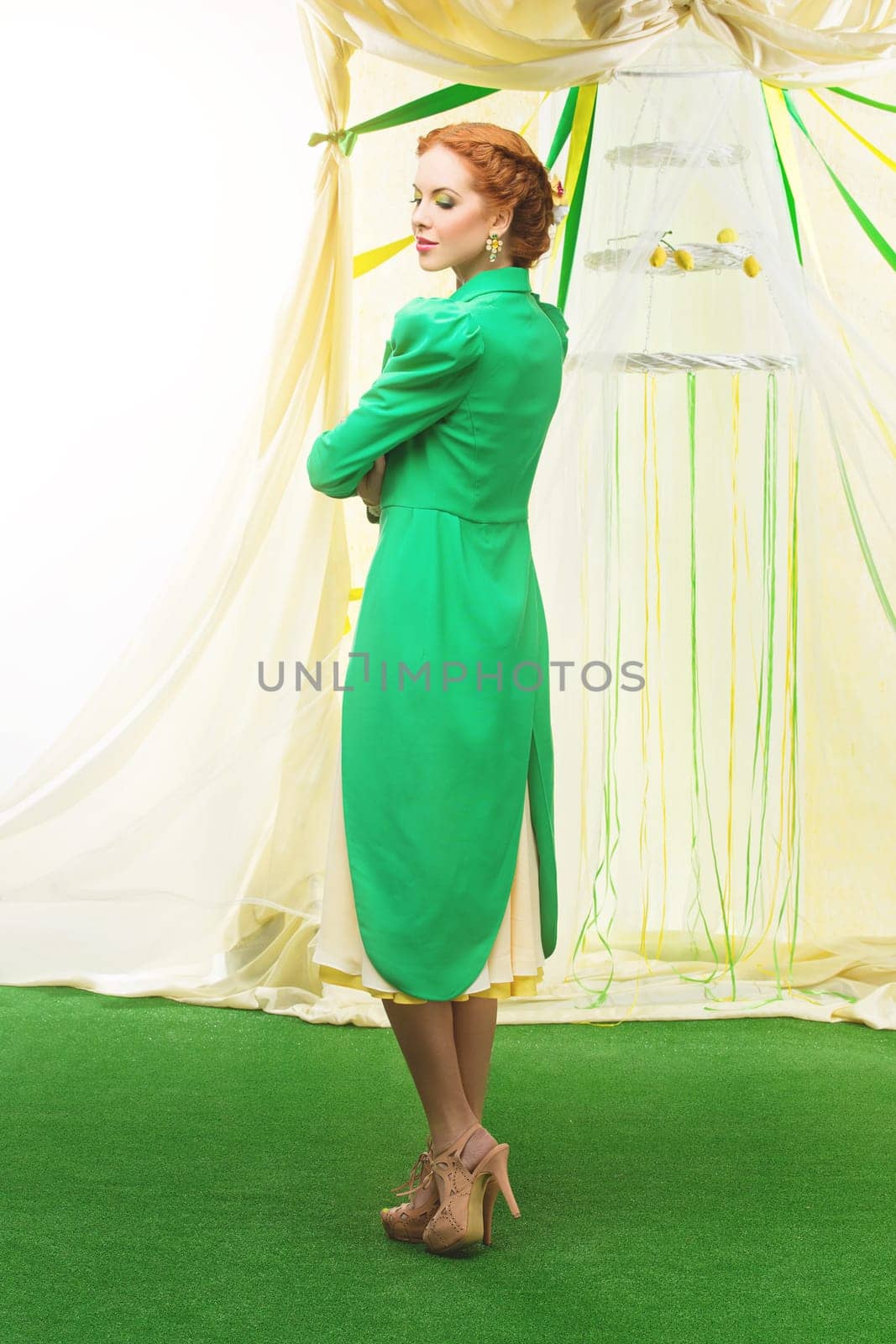 Beautiful young woman with makeup in yellow dress and green tail coat. Wedding arch on background. Copy space.
