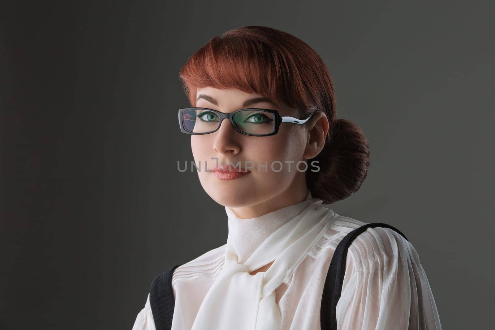 Closeup of beautiful young woman in white blouse and glasses over grey background