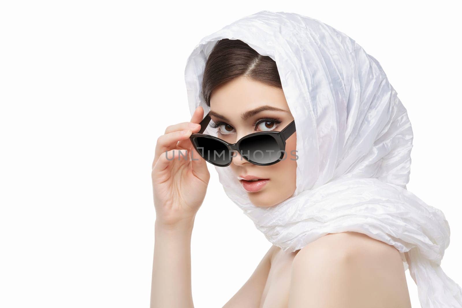 Closeup portrait of beautiful young woman in white scarf on head holding black sunglasses. Isolated over white background. Copy space.