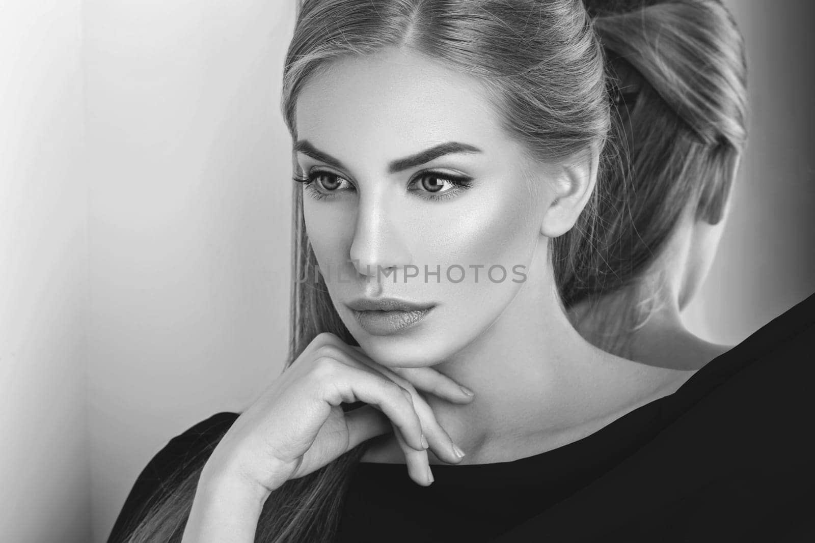 Beautiful young woman with blond hair and makeup covered with piece of black fabric. Copy space.