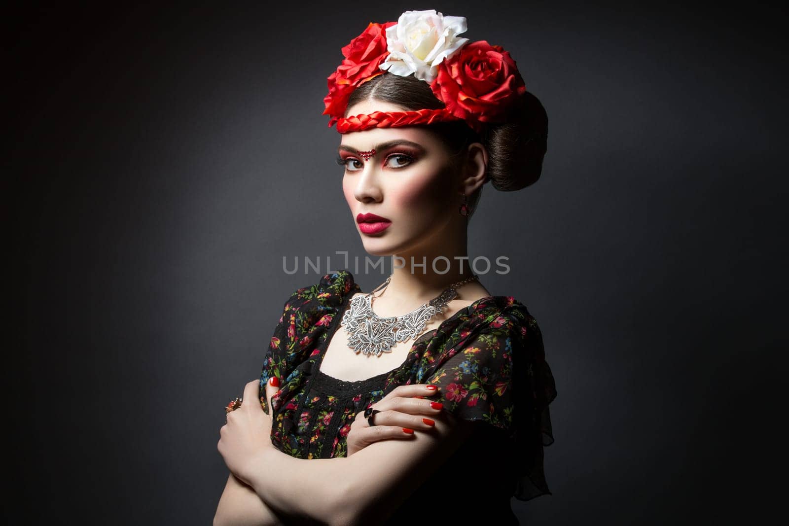 Beautiful young woman with bright red make up looking like Frida Kahlo. Over black background. Copy space.