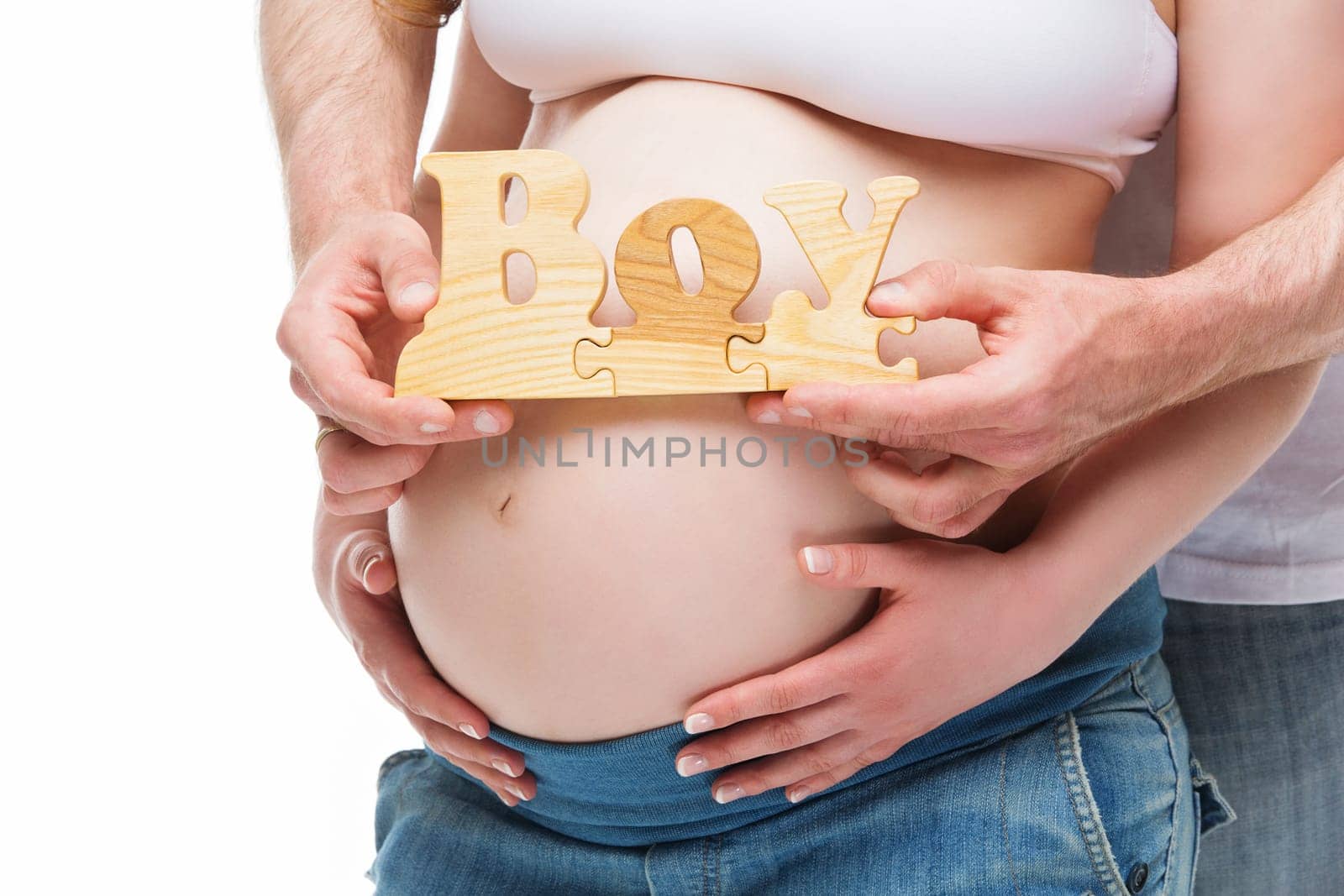 Closeup of young pregnant woman belly and man hands holding word boy over it. Isolated on white background.