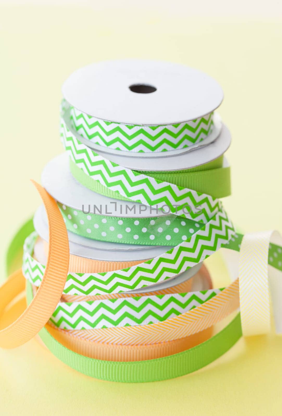 Colorful rolls gift ribbon stacked on yellow background