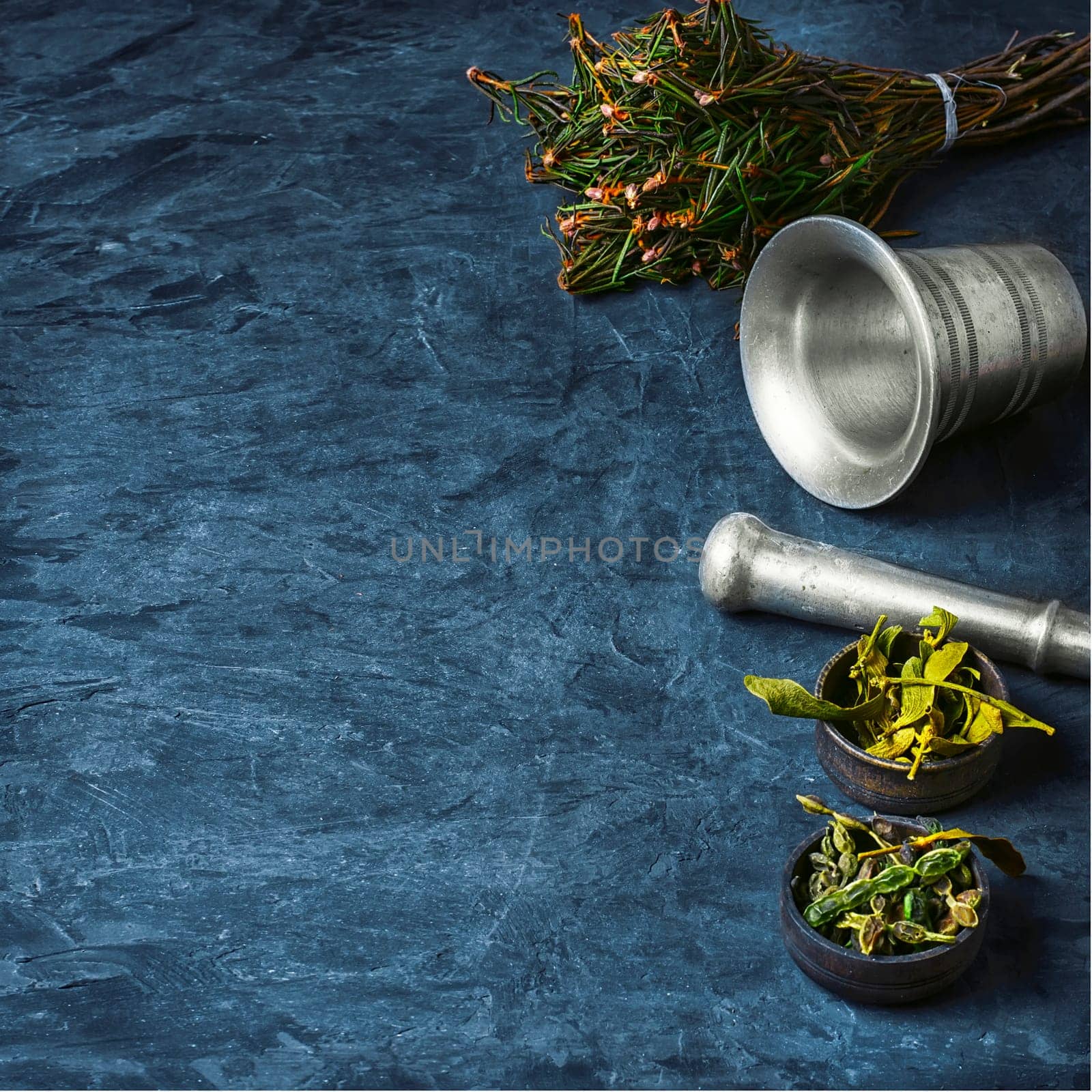 Bundle herbs and mortar with pestle on slate background.Copy space