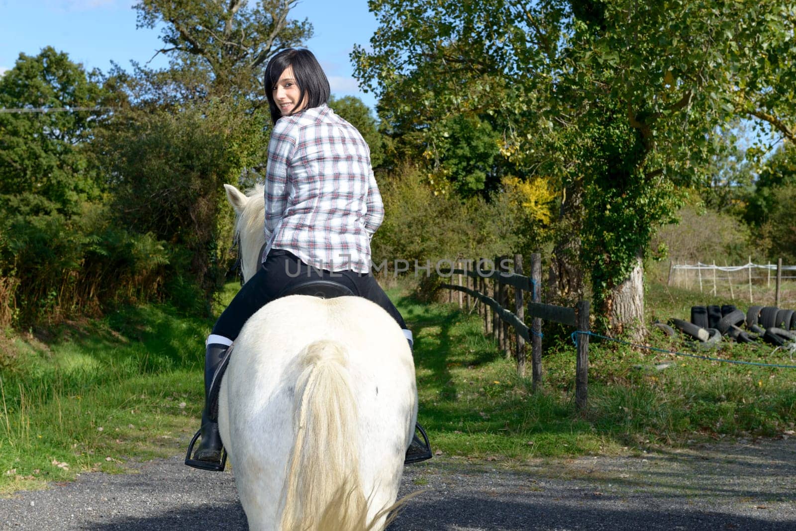young beautiful brunette woman riding white horse