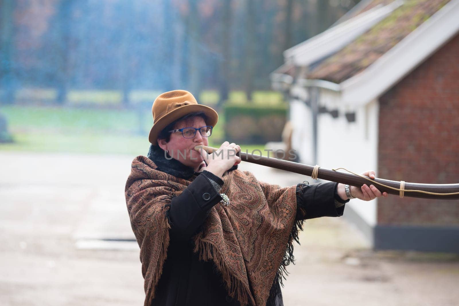 OLDENZAAL, NETHERLANDS - NOVEMBER 27, 2016: Unknown woman blowing a so called "midwinterhorn"", a traditional handmade wooden instument. It is used in the advent period in some eastern parts of the netherlands"
