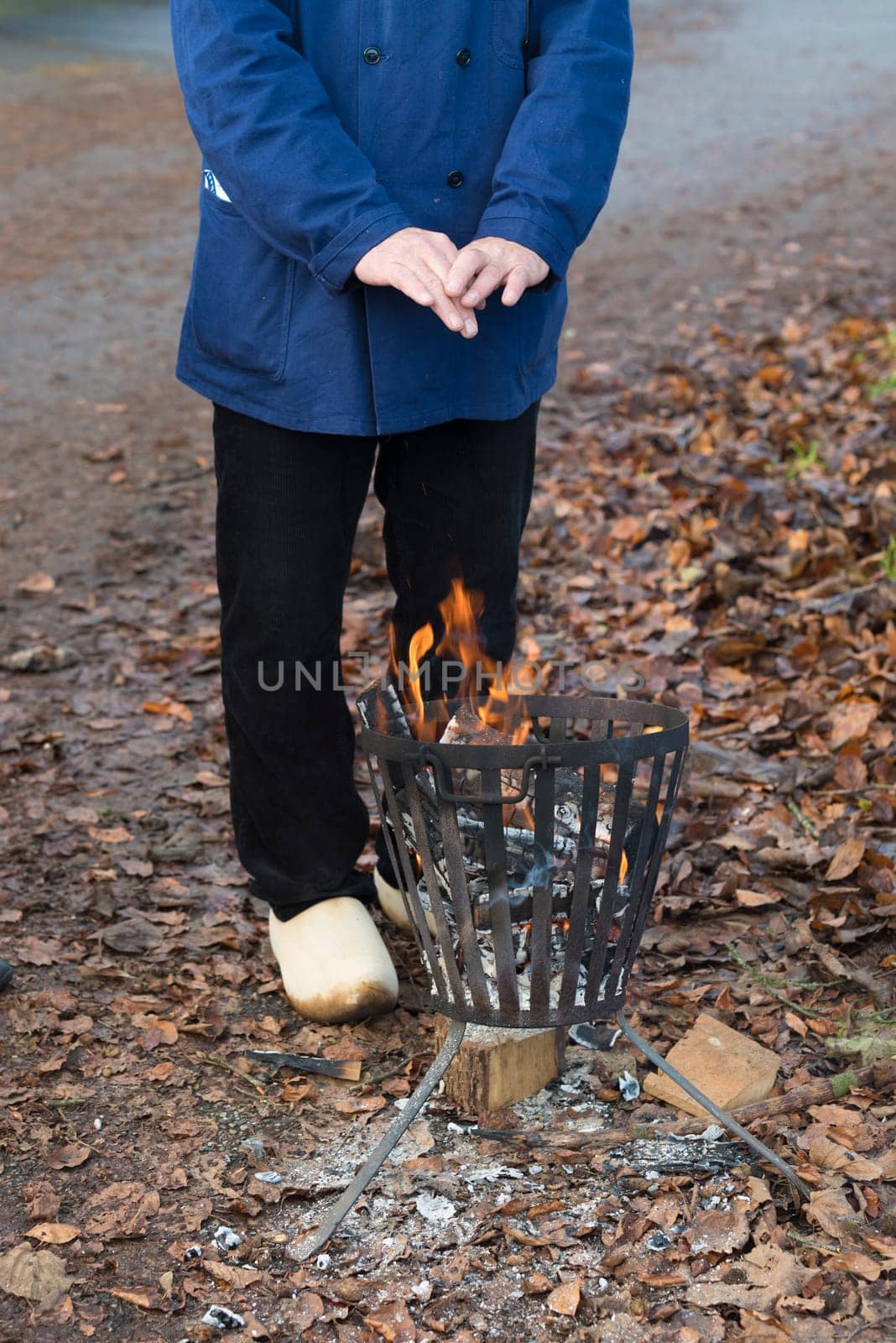 person warming his hands on a metal fire pit