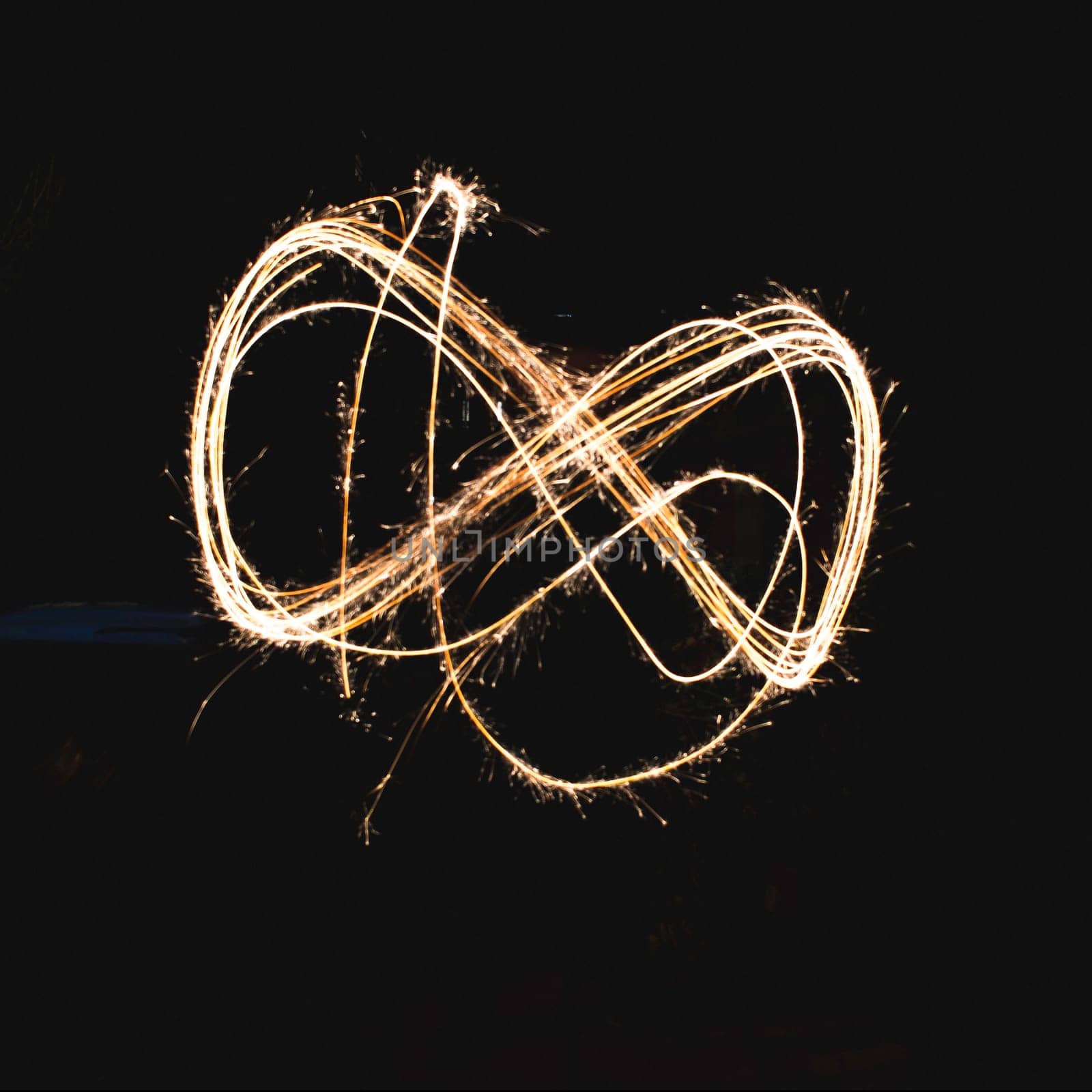 infinite shape made with a sparkler in a garden, using long exposure.