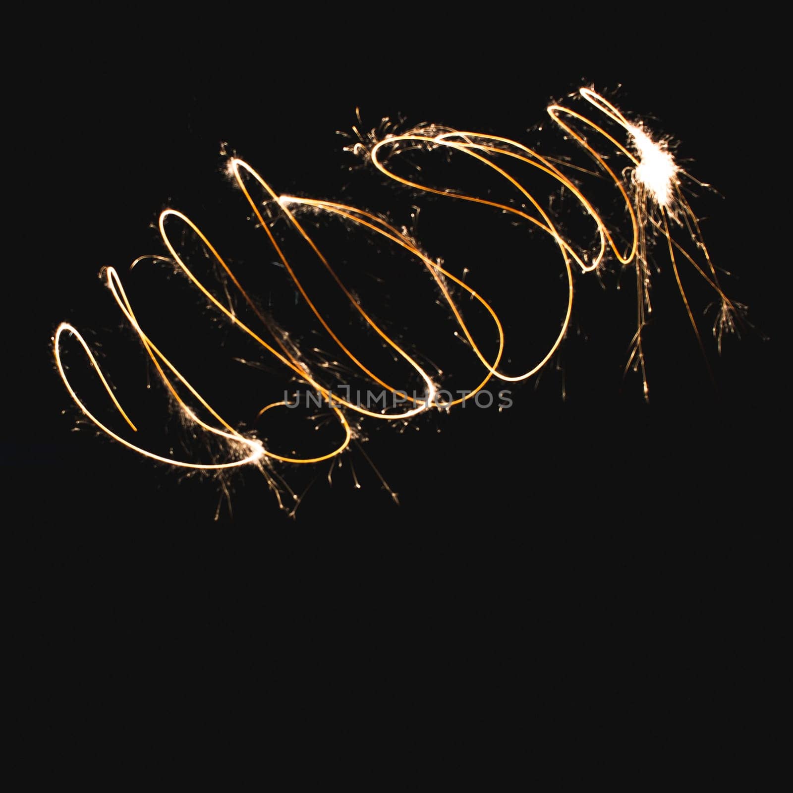 Squiggle shapes made with a sparkler in a garden, using long exposure.