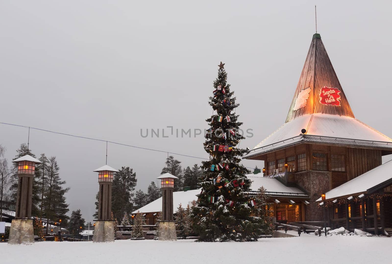 Santa Claus Village in Rovaniemi on a cloudy day in January 2015. Christmas tree decorated with flags of the countries.