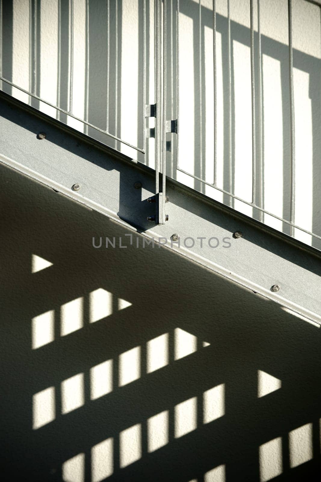 The façade of a residential building with an external staircase that casts a shadow.