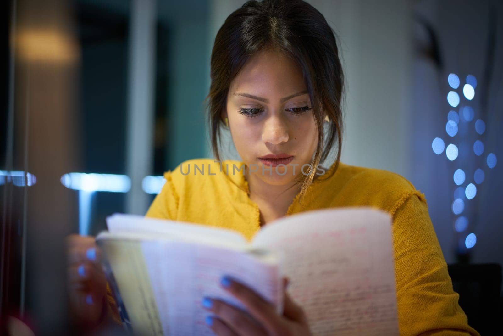 Young woman doing homework at night. Tired hispanic girl and college education. Female student studying for next day exam