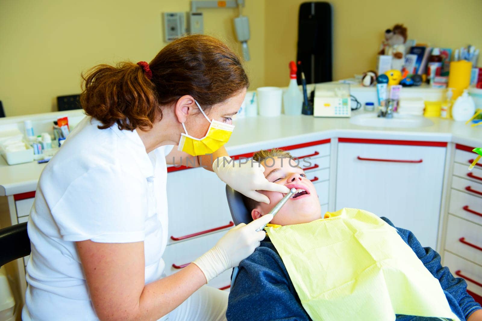 teenager is treated by female dentist in dental surgery