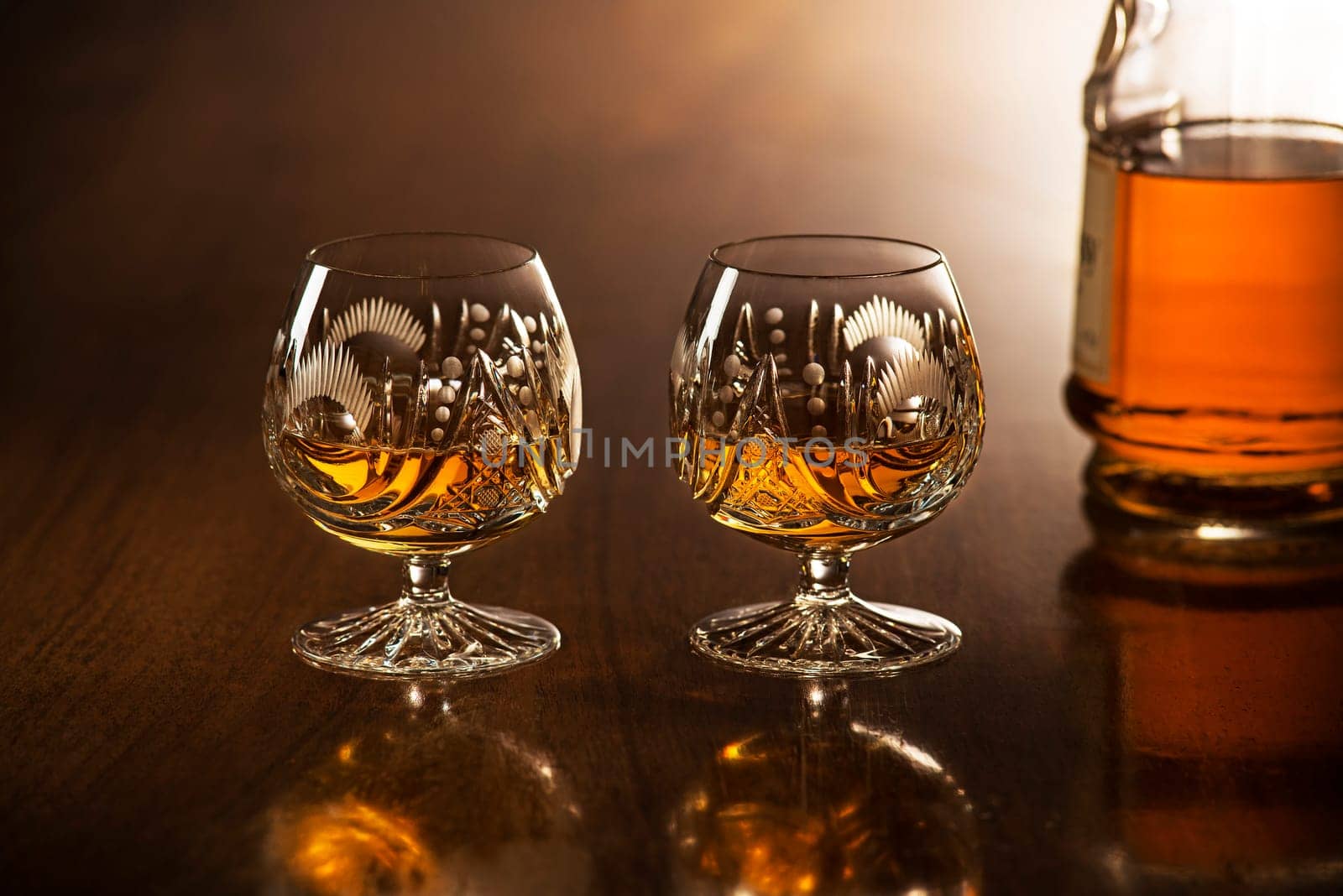 Cognac in glass with bottle on wooden table