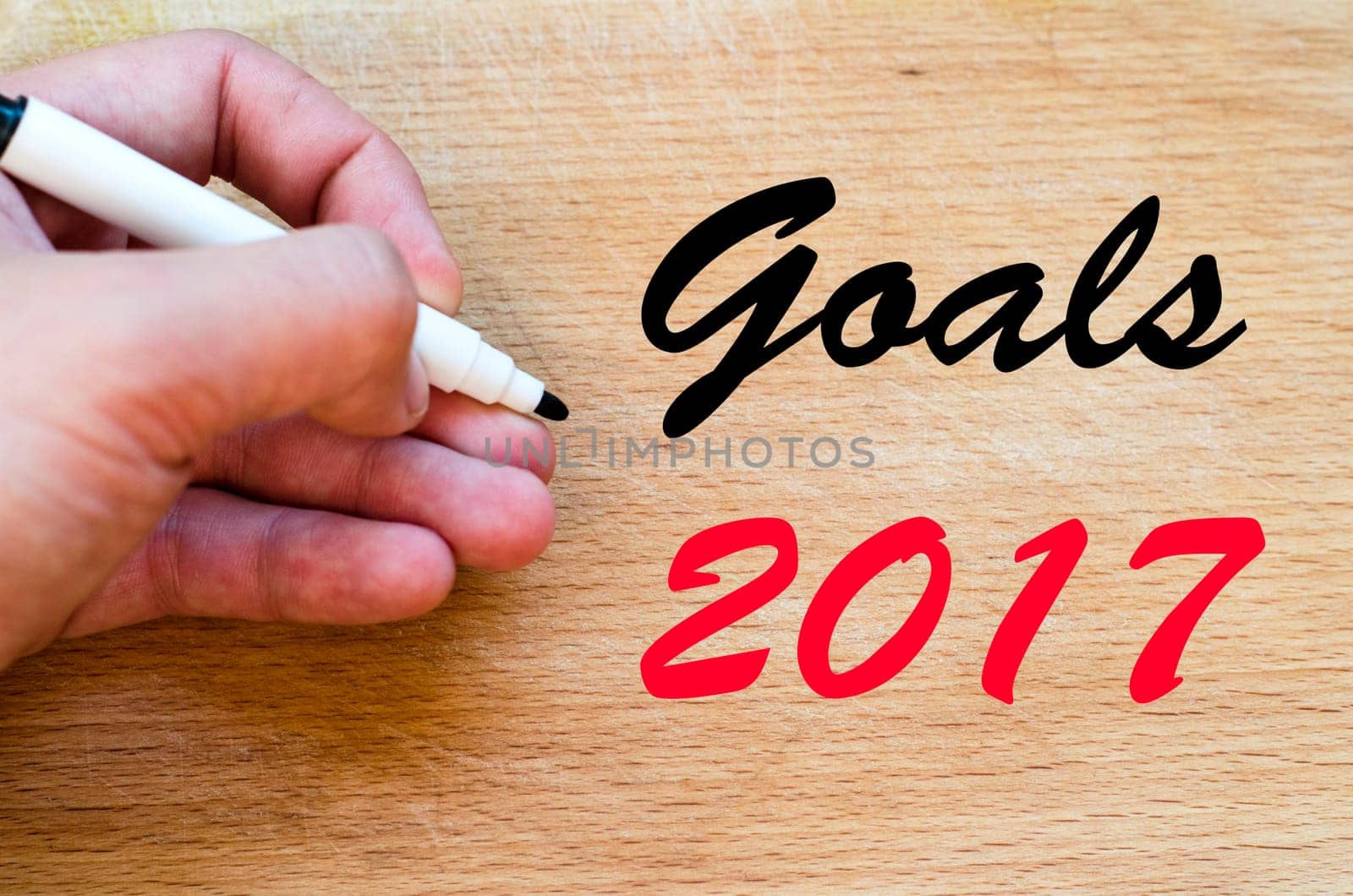Human hand over wooden background and goals 2017 text concept